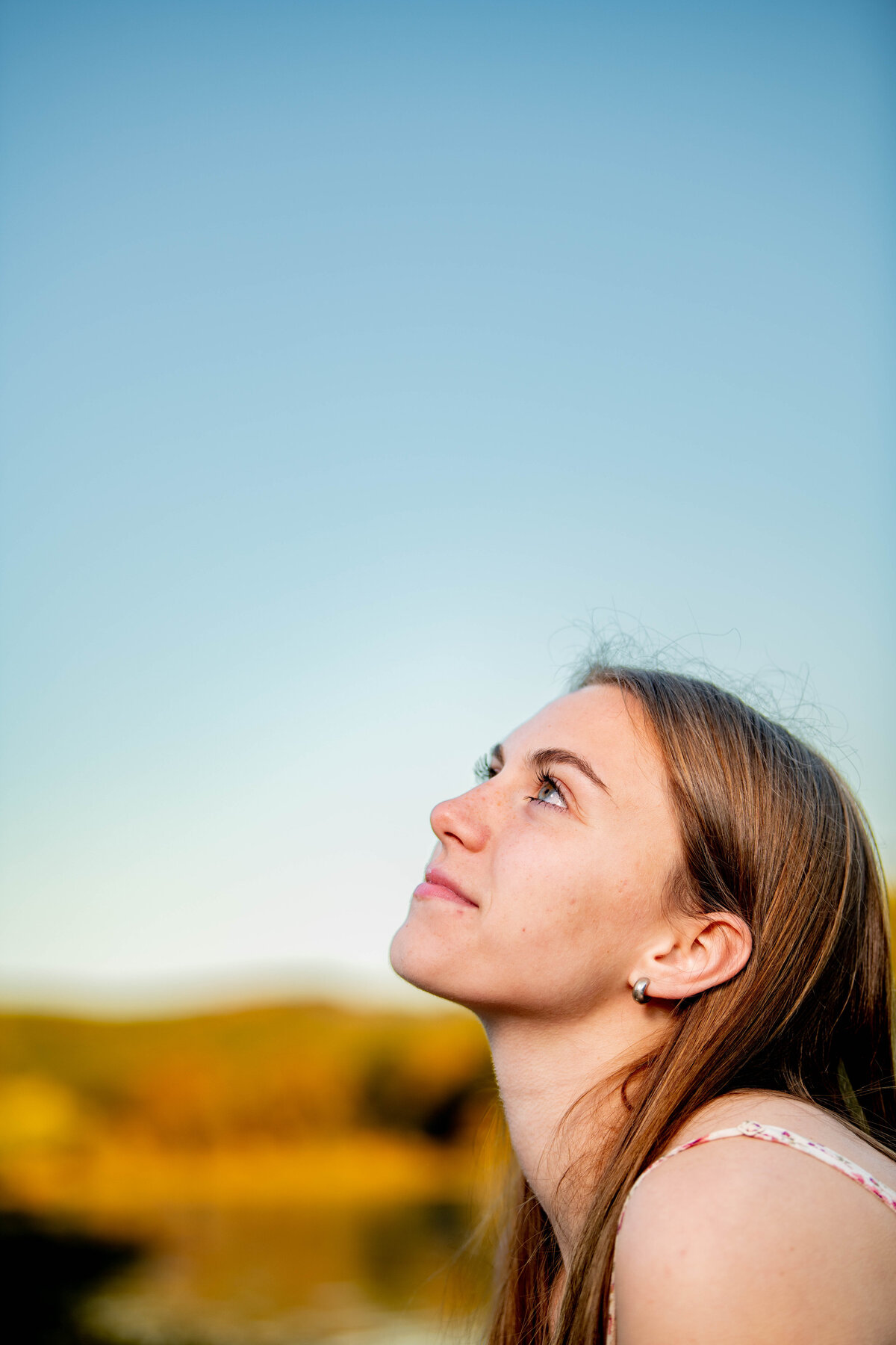 a profile of a girl's face is seen smiling toward the sky
