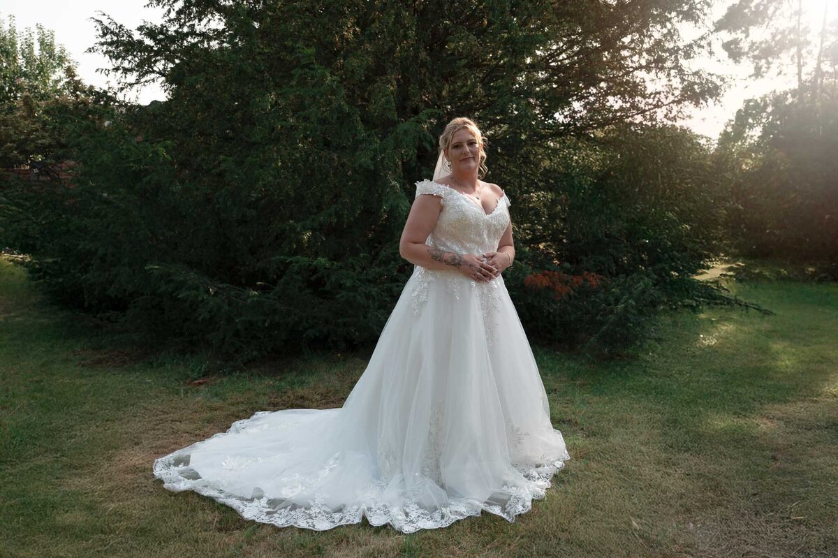 Bride smiling in lace gown during garden portraits – Cheshire bridal photography.