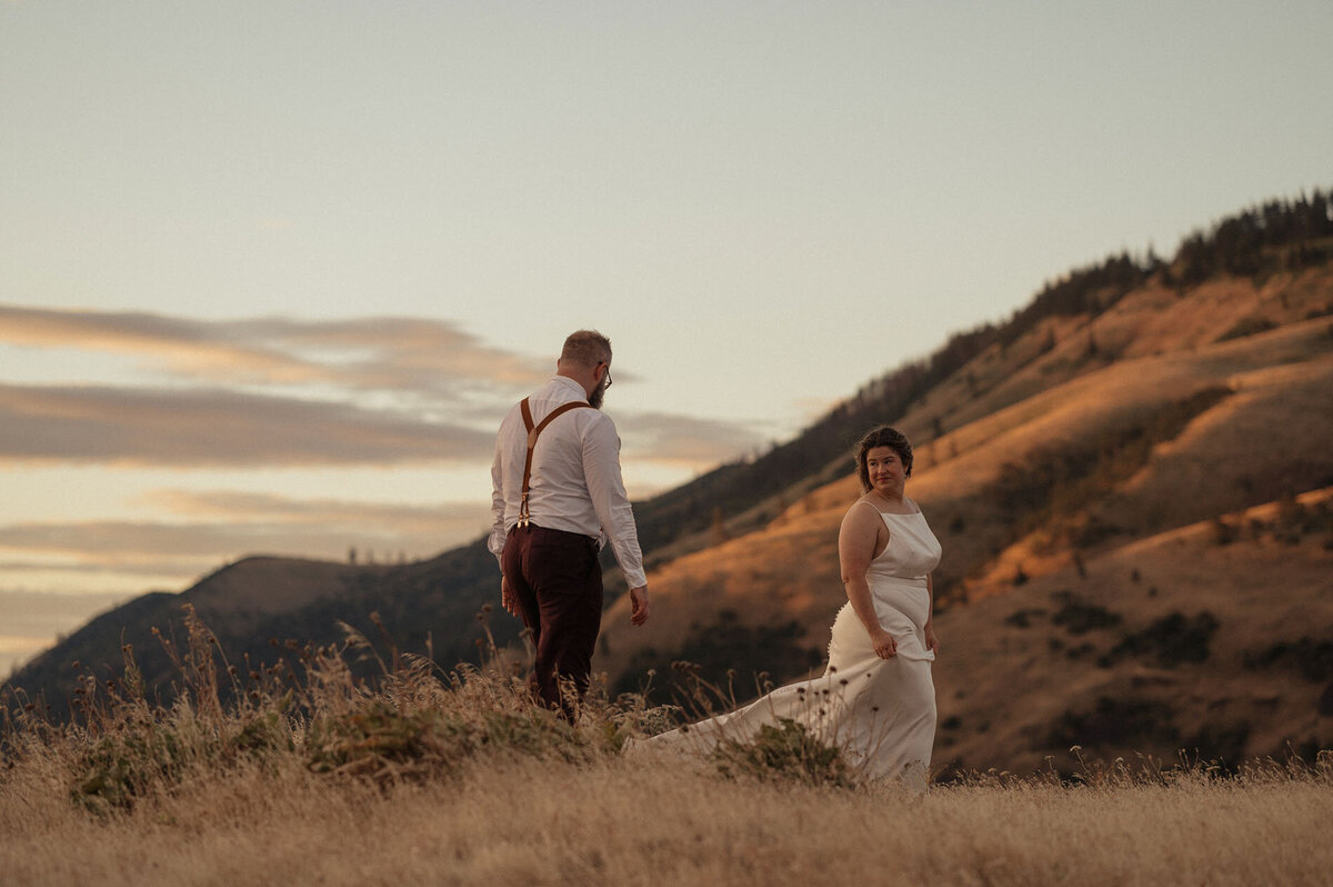 intimate elopement couple walking amongst tall grasses under the sunset sky in the Dalles, OR