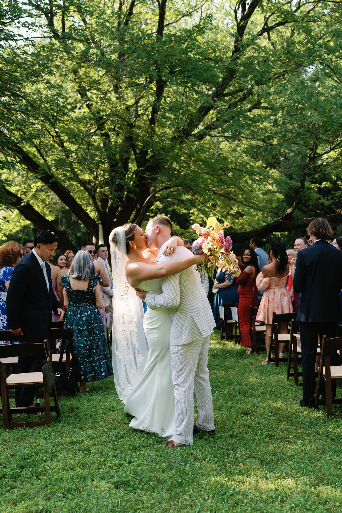 A bride and groom share a kiss at the end of the aisle during their backyard wedding ceremony in Nashville Tennessee. 