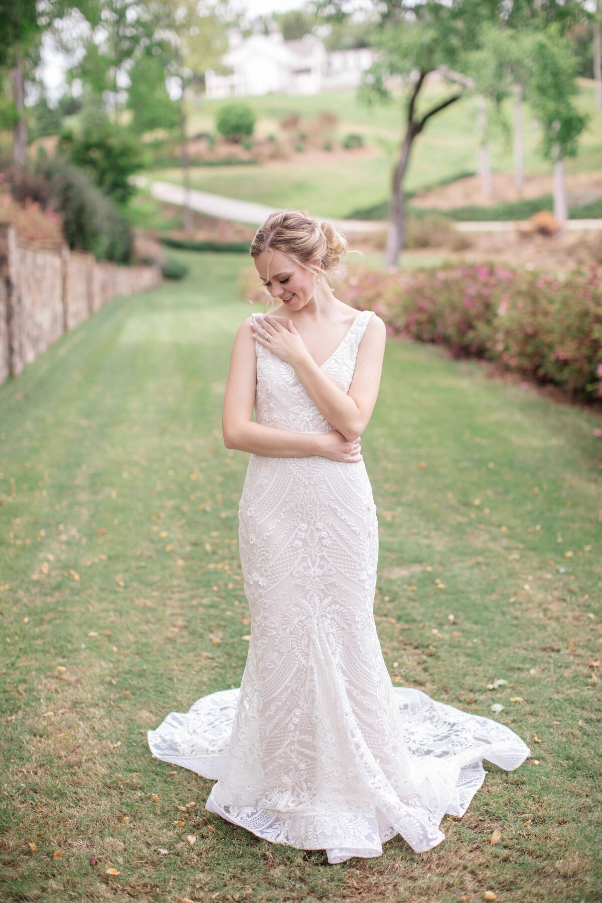 bride in v neck gown smiles at ring along path by wedding photographer in Texas