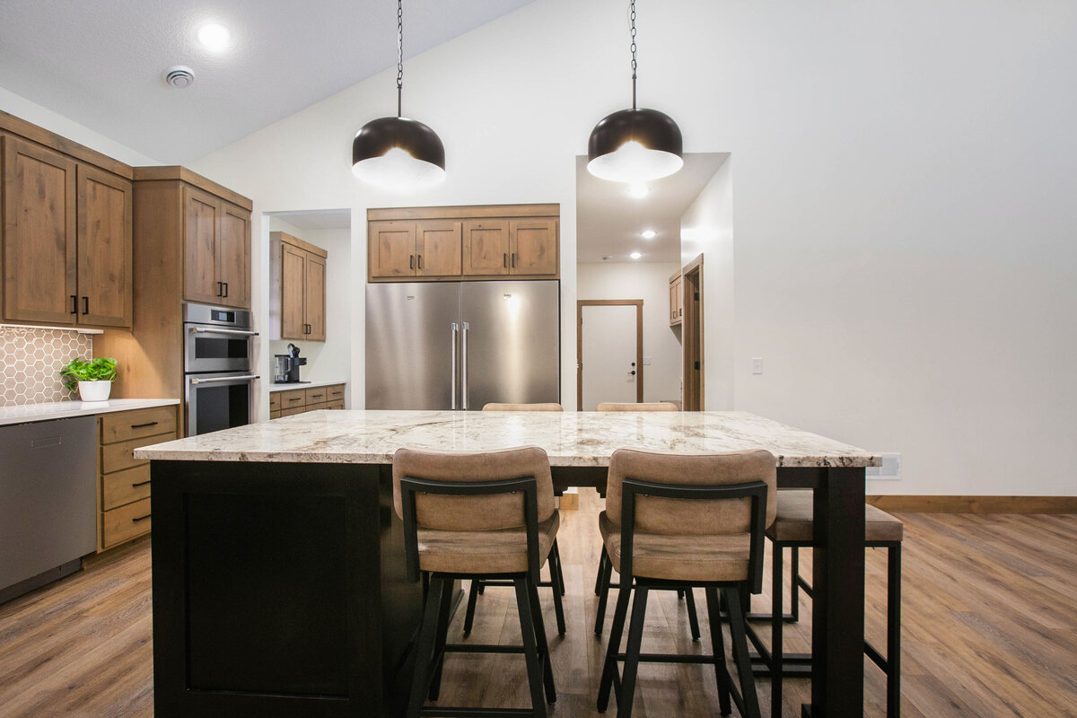 Open kitchen with dark cabinets, large island, and quartz countertops in an Elk River custom home