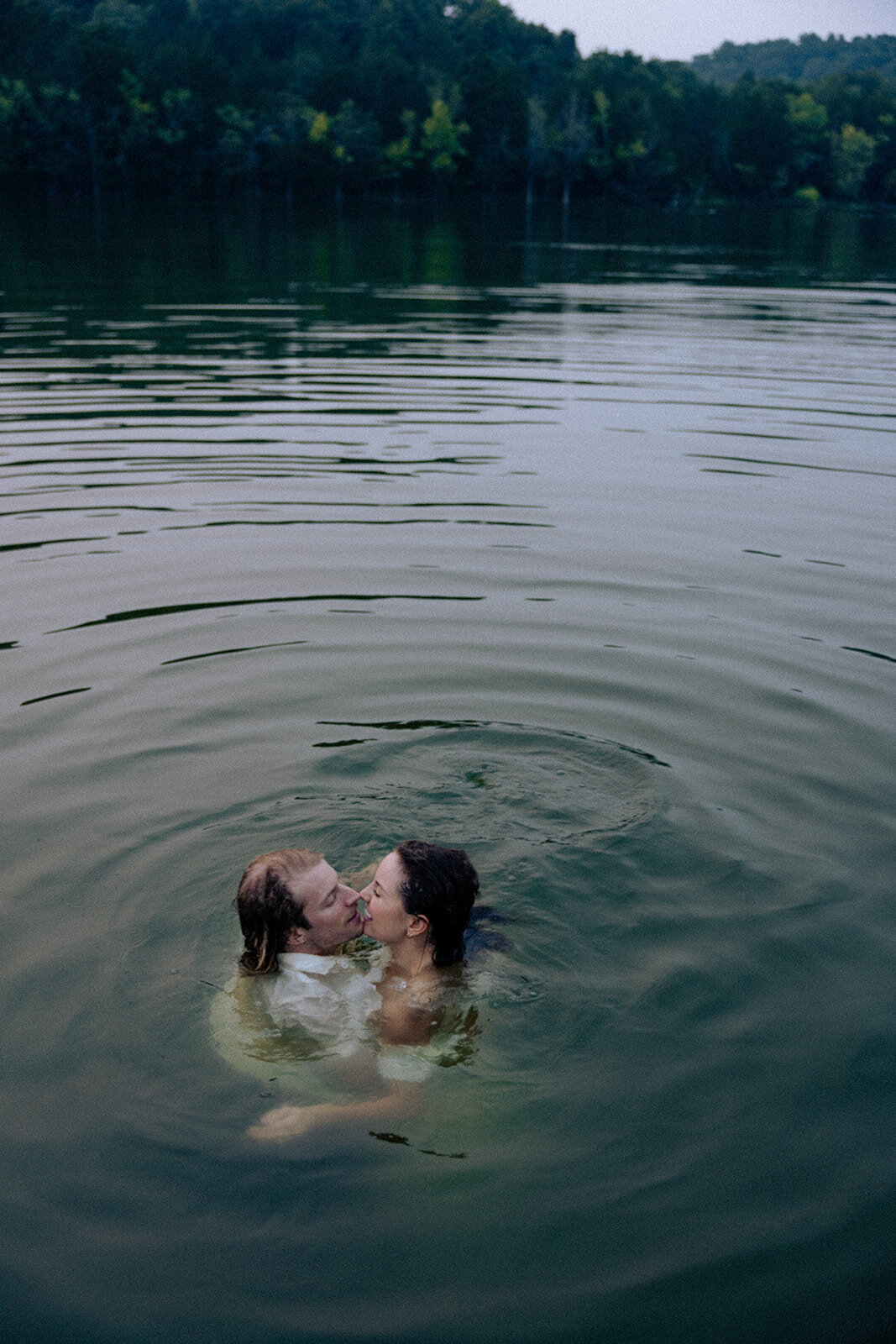 Candid engagement photo session featuring couple swimming in lake in Nashville, TN. 