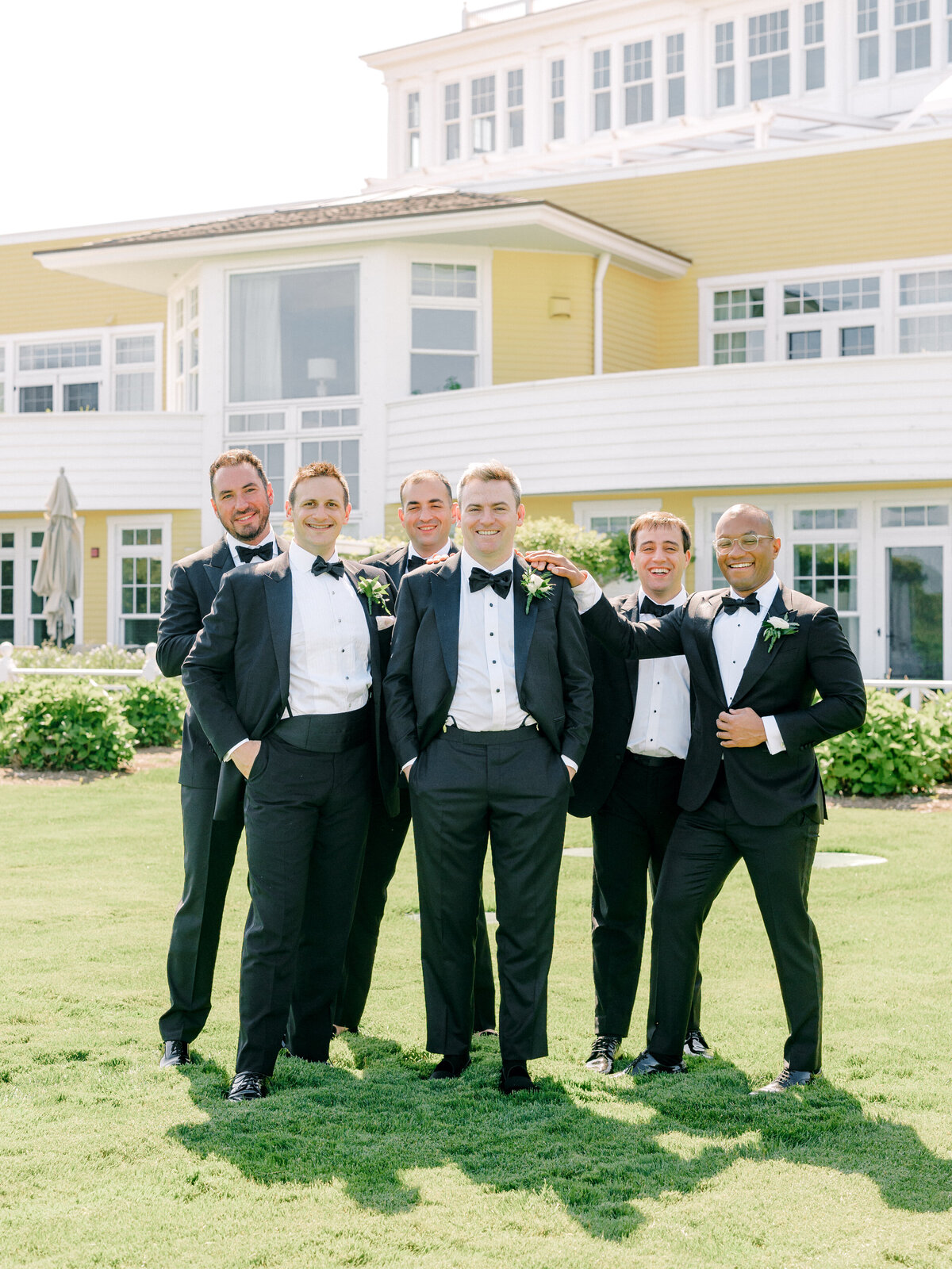 Group photo of groom and his groomsmen in front of a yellow building