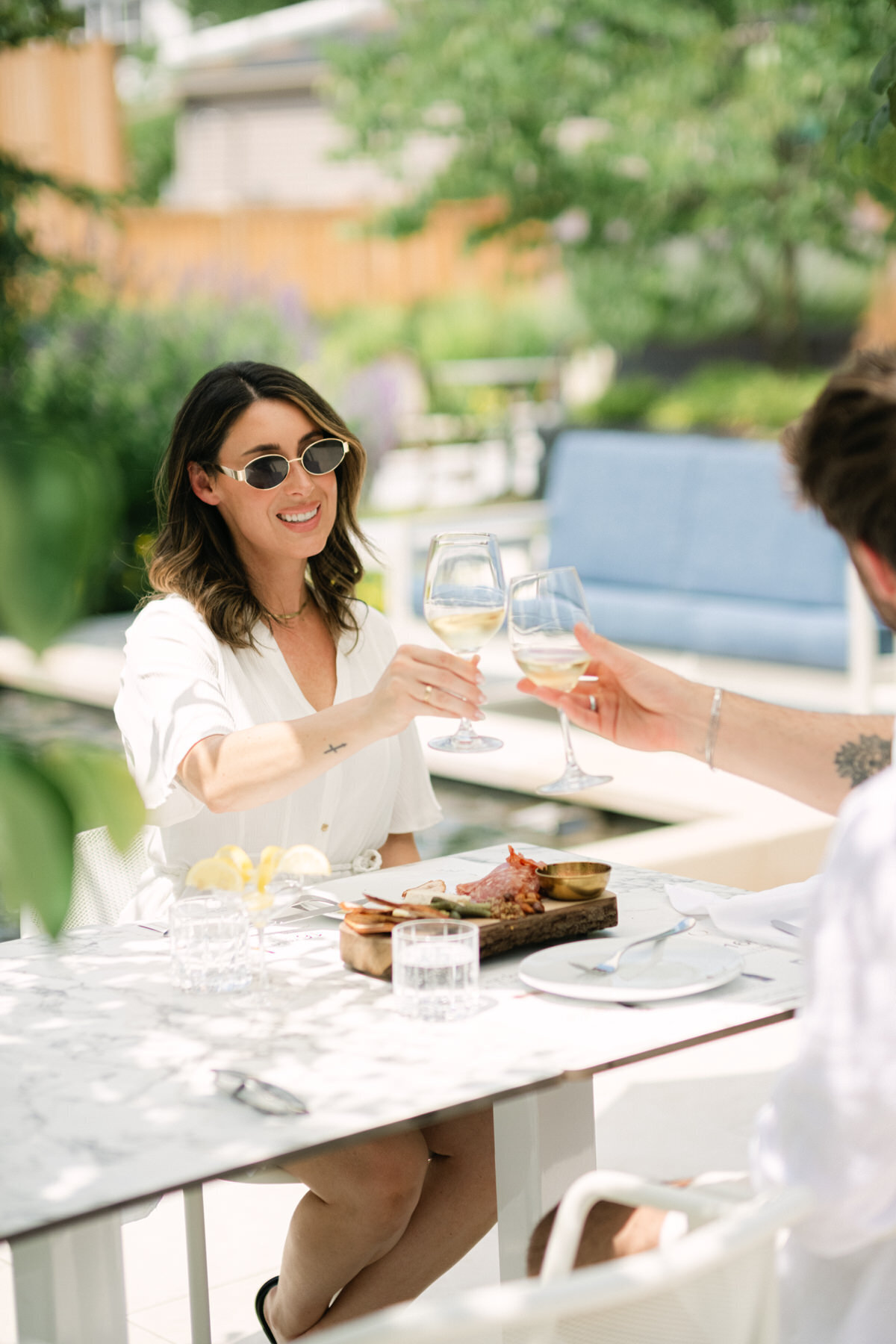 Influencer photo of couple clinking glasses outdoors on patio for branding photos