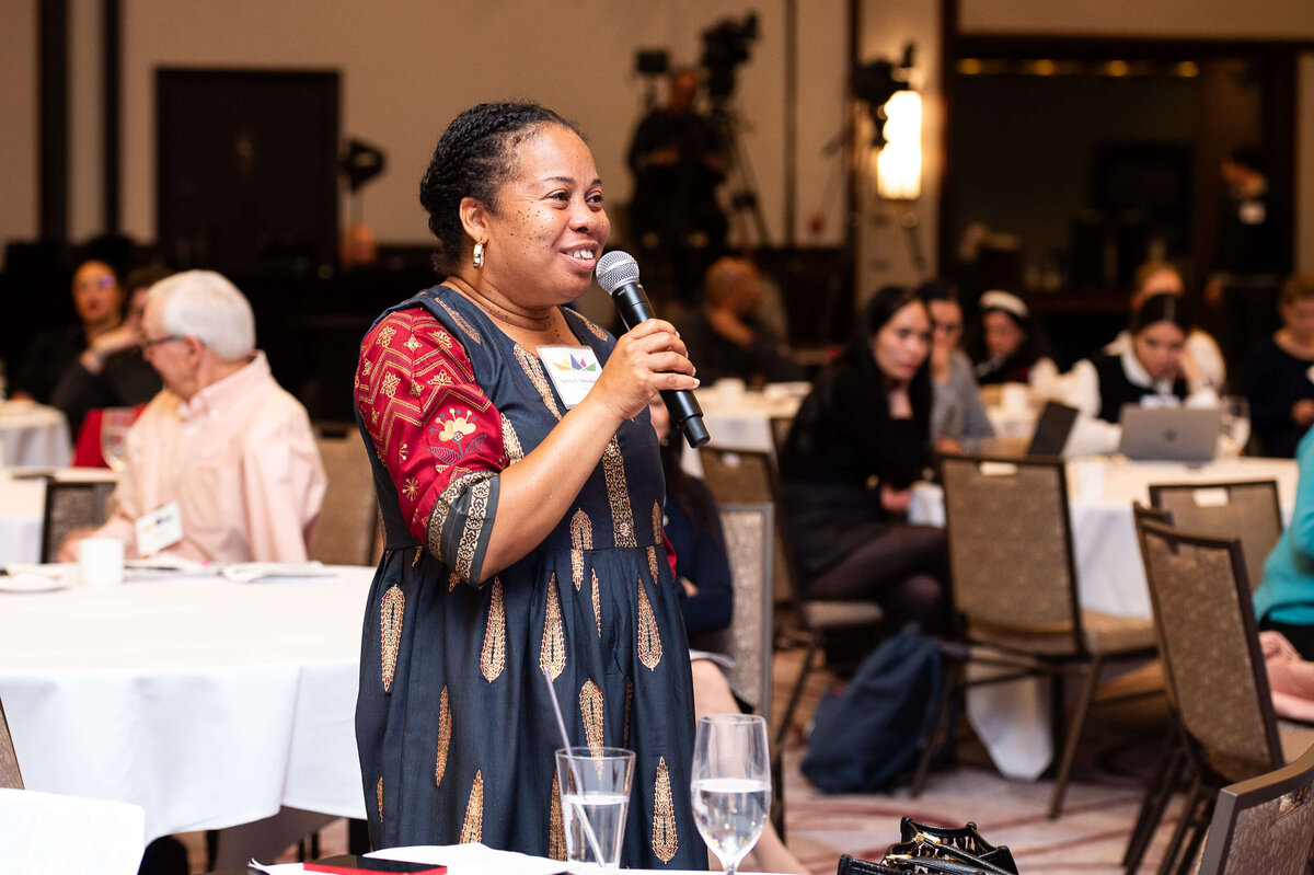 Ottawa event photography showing a black woman smiling and talking into a microphone during question period of a corporate conference.  Captured by JEMMAN Photography COMMERCIAL