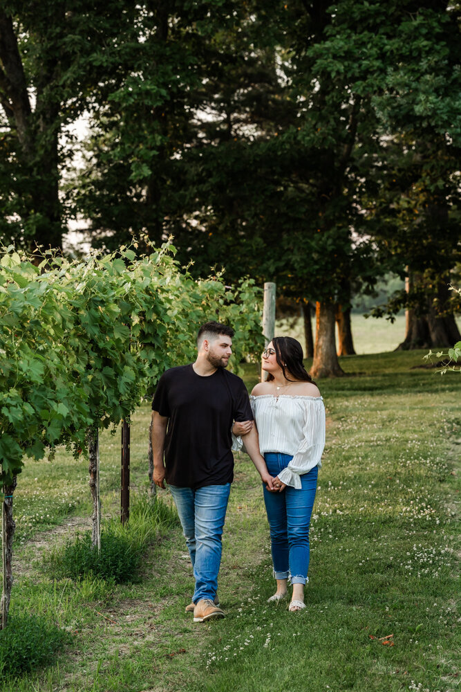 Couple casually strolling through a row of grape vines