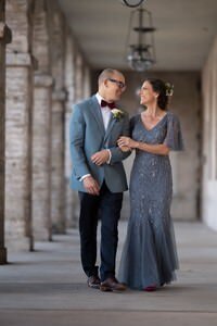 Elegant couple in formal attire walking arm-in-arm through historic St Augustine colonnade, captured by professional elopement photographers