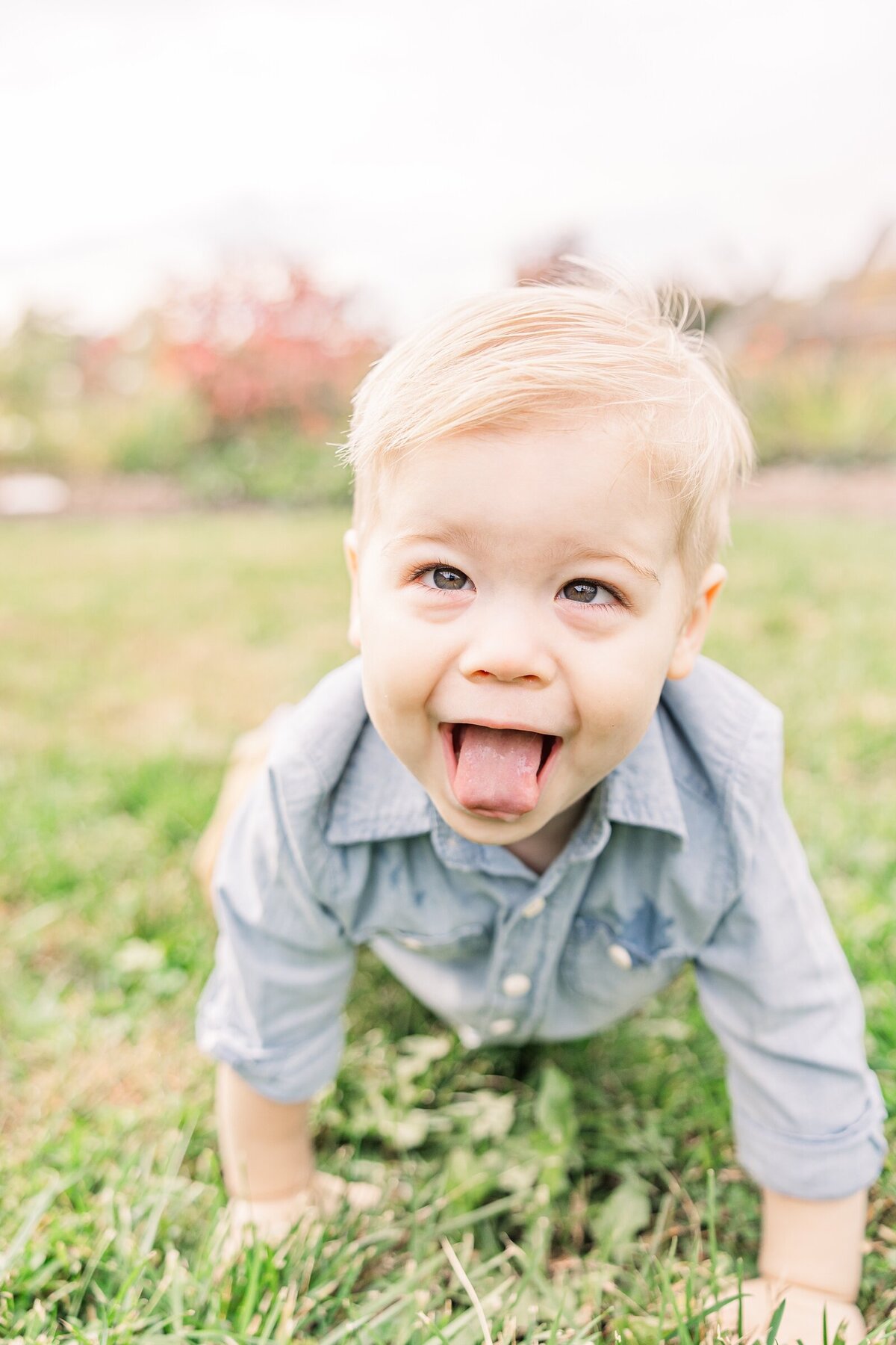 Little boy crawling in the grass with his tongue hanging out of his mouth