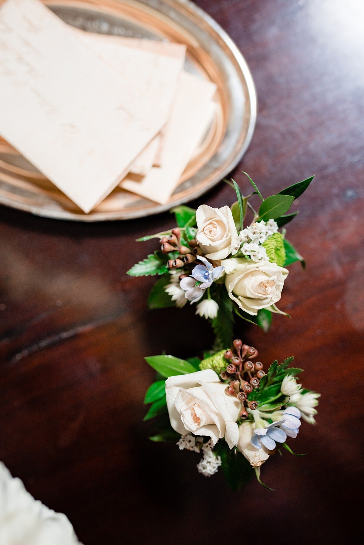 two white rose boutonnieres with berries and dusty miller. Two groomsmen boutonnieres.