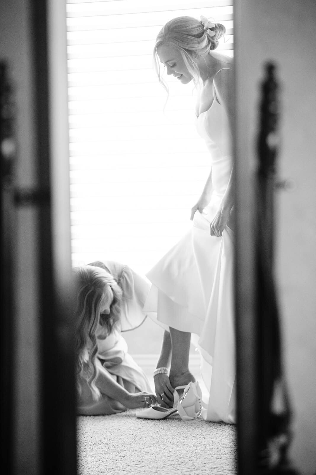  A woman helping a bride into her heeled shoes.