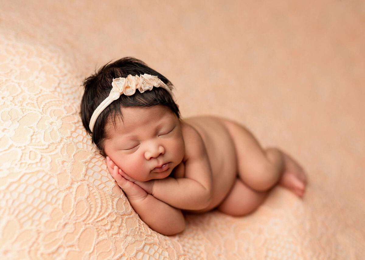 Newborn girl posed on a beautiful peach floral fabric during her newborn session in Southern Minnesota.