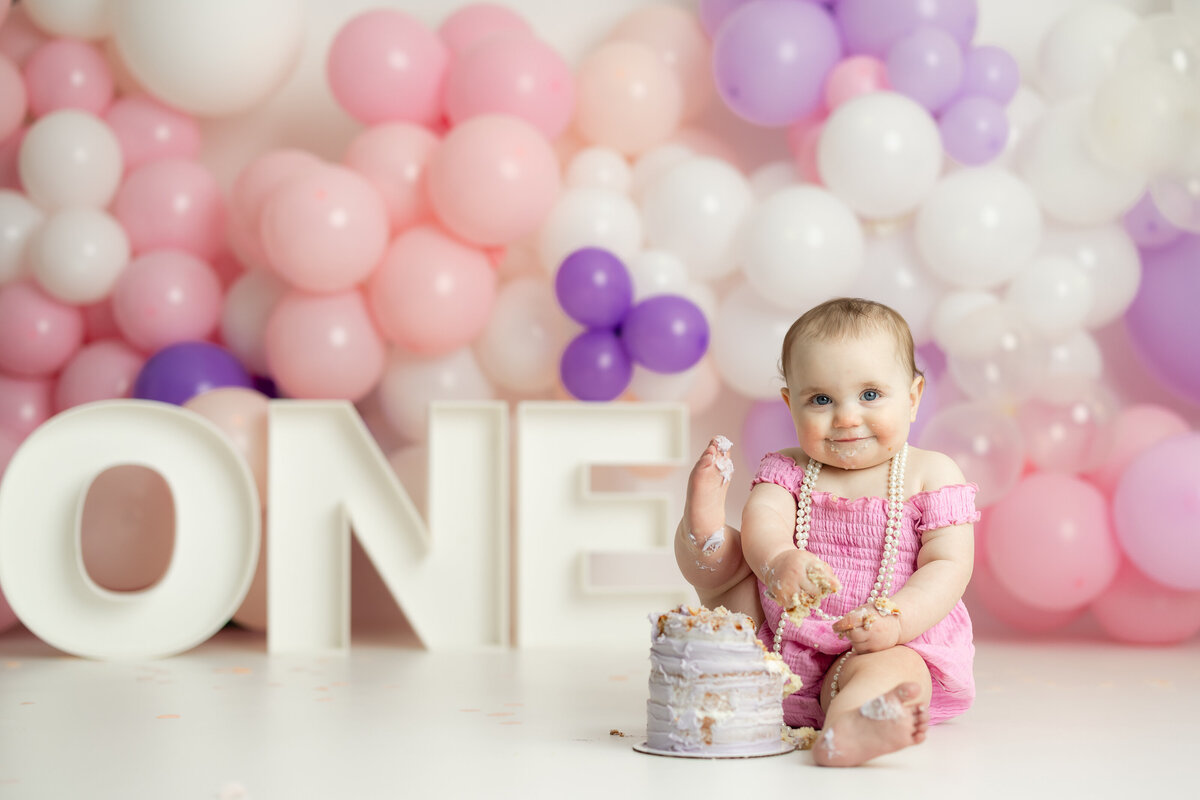  Baby girl with pink and purple balloon arch during first birthday cake smash in Canton GA
