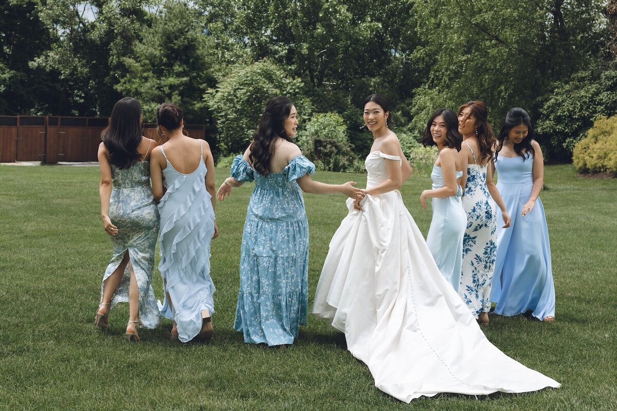 Bride laughing with bridesmaids dressed in light blue on the lawn