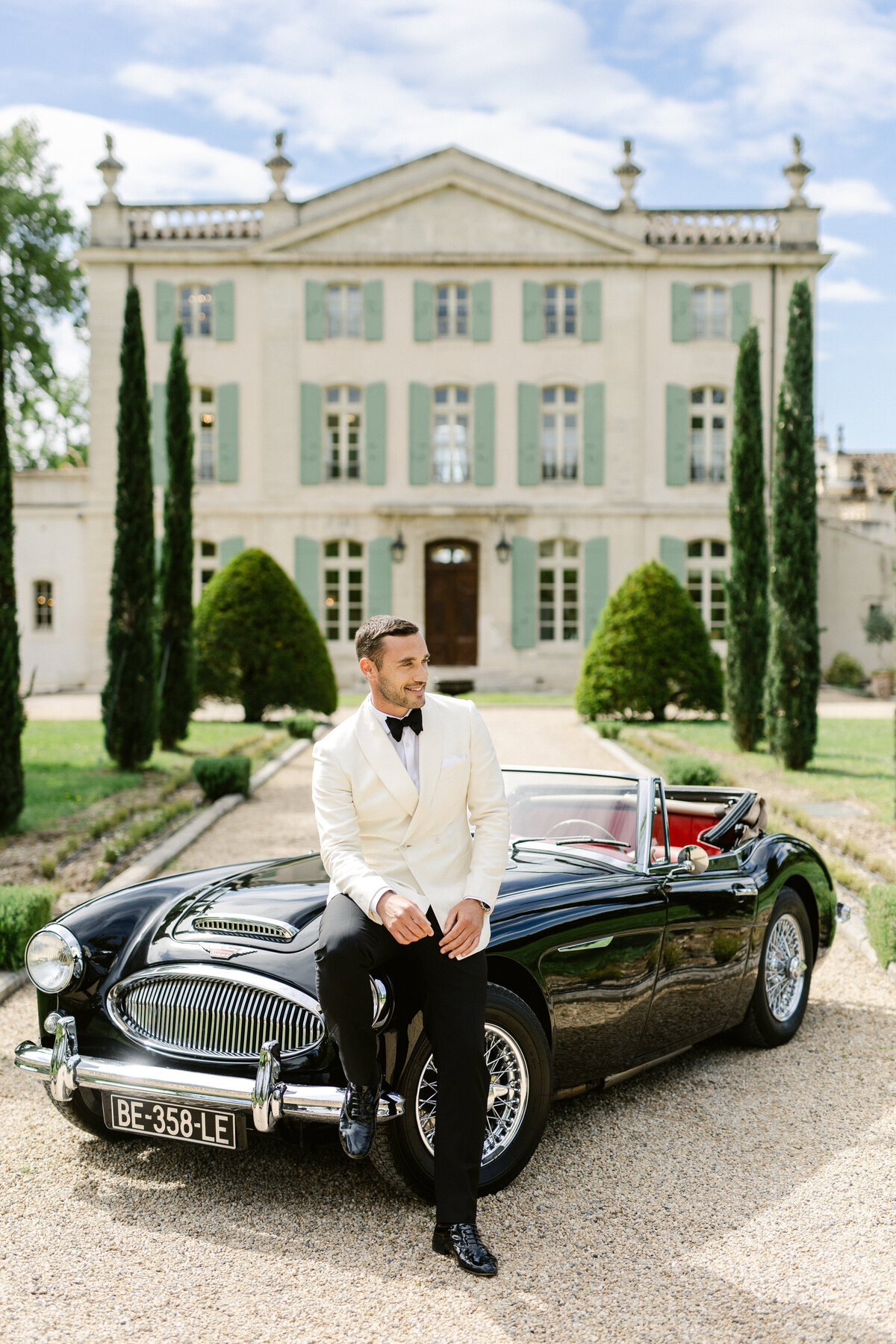 Le marié assis sur une voiture ancienne devant le Château de Tourreau, photographié par Marion Pinel
