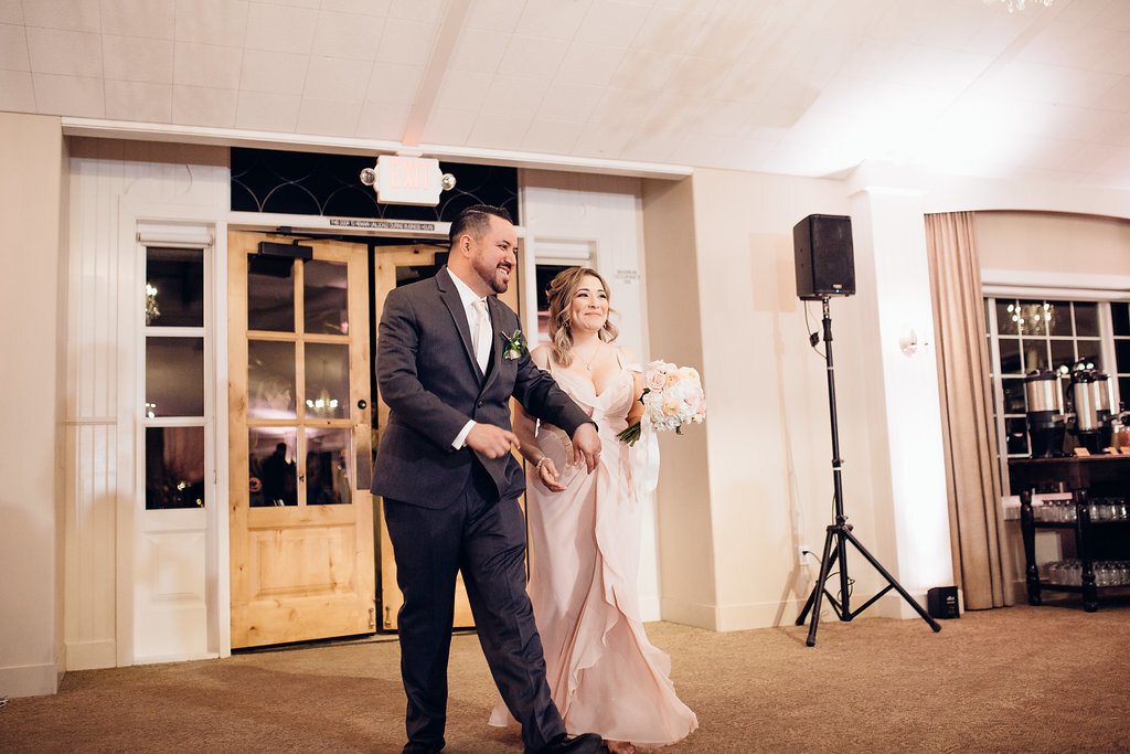 Wedding Photograph Of Groomsman And Bridesmaid Carrying a Bouquet Inside The Reception Hall Los Angeles