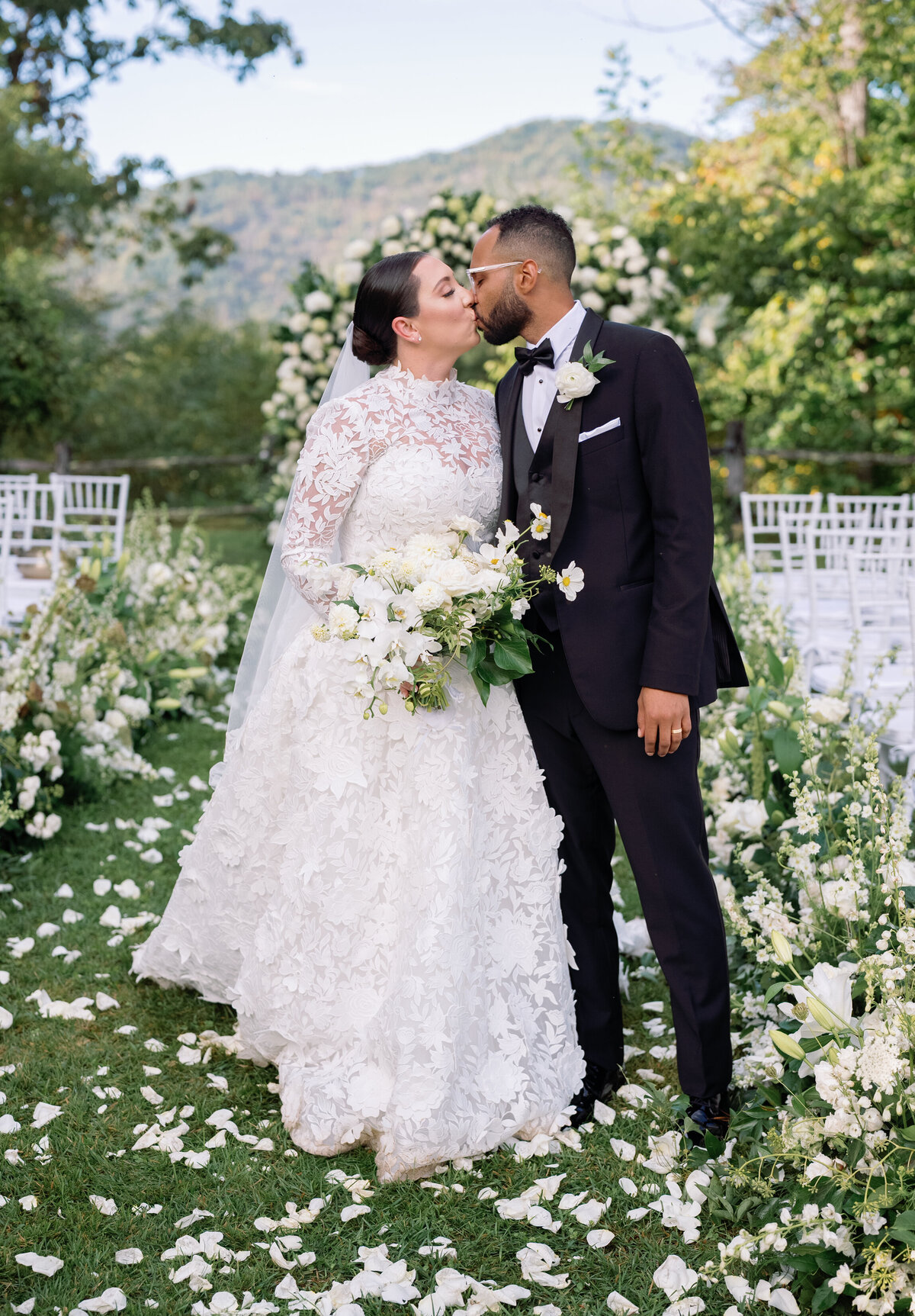 Bride and groom sharing a kiss in the ceremony aisle surrounded by white florals at Castle Ladyhawke.