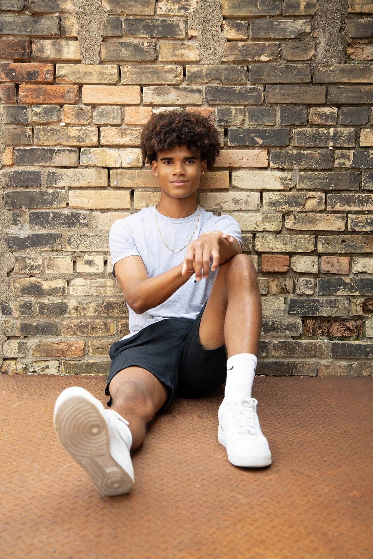 casual-senior-guy-sitting-by-urban-brick-wall