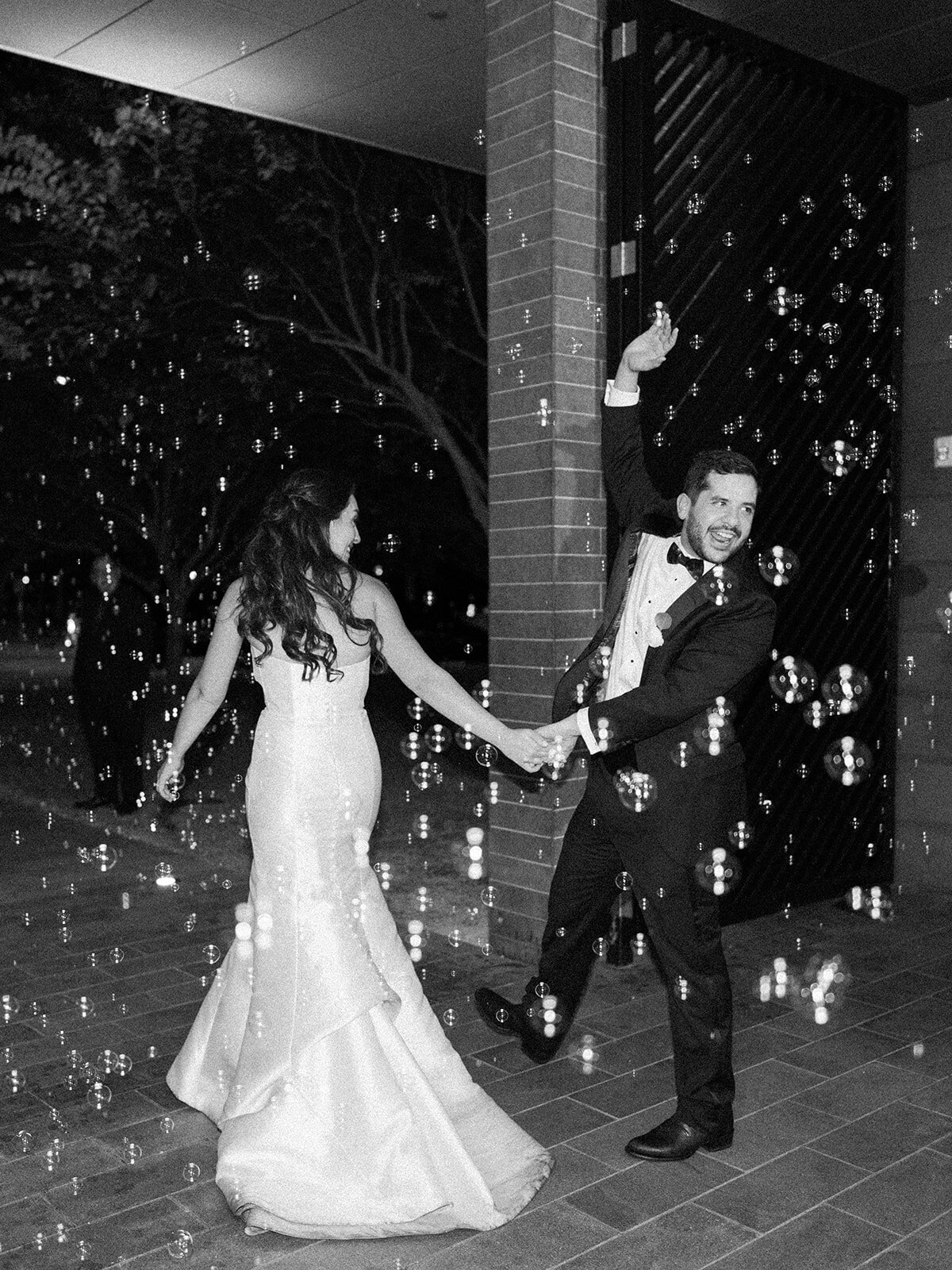 Black and white photo of bride and groom leaving their reception surrounded by bubbles