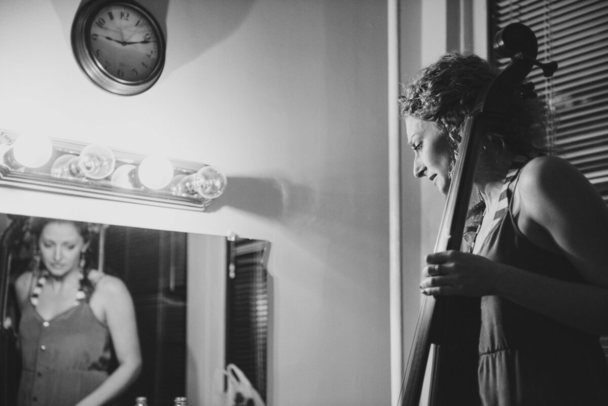 A person standing in a dressing room while holding a cello