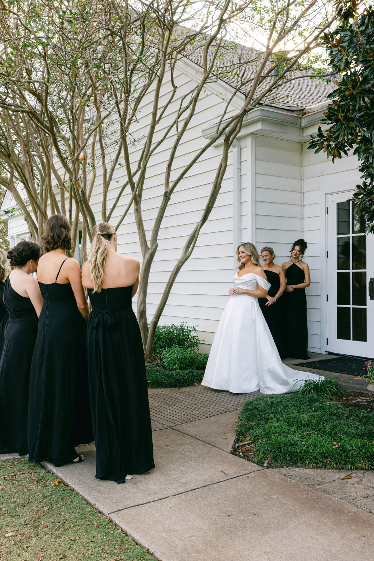 A wedding photo of the bridesmaids seeing the bride in her dress for the first time