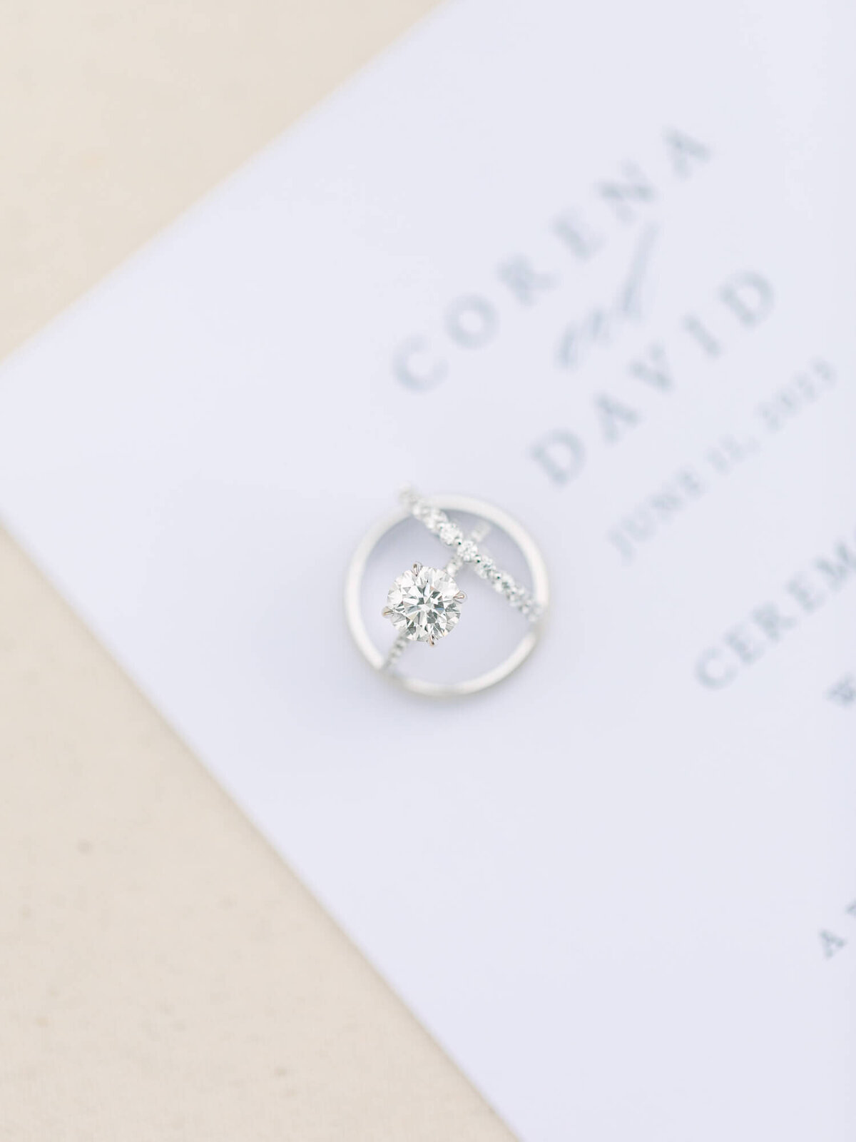 A sparkling engagement ring and wedding band lie on an elegant wedding invitation, conveying a sense of romance and anticipation.