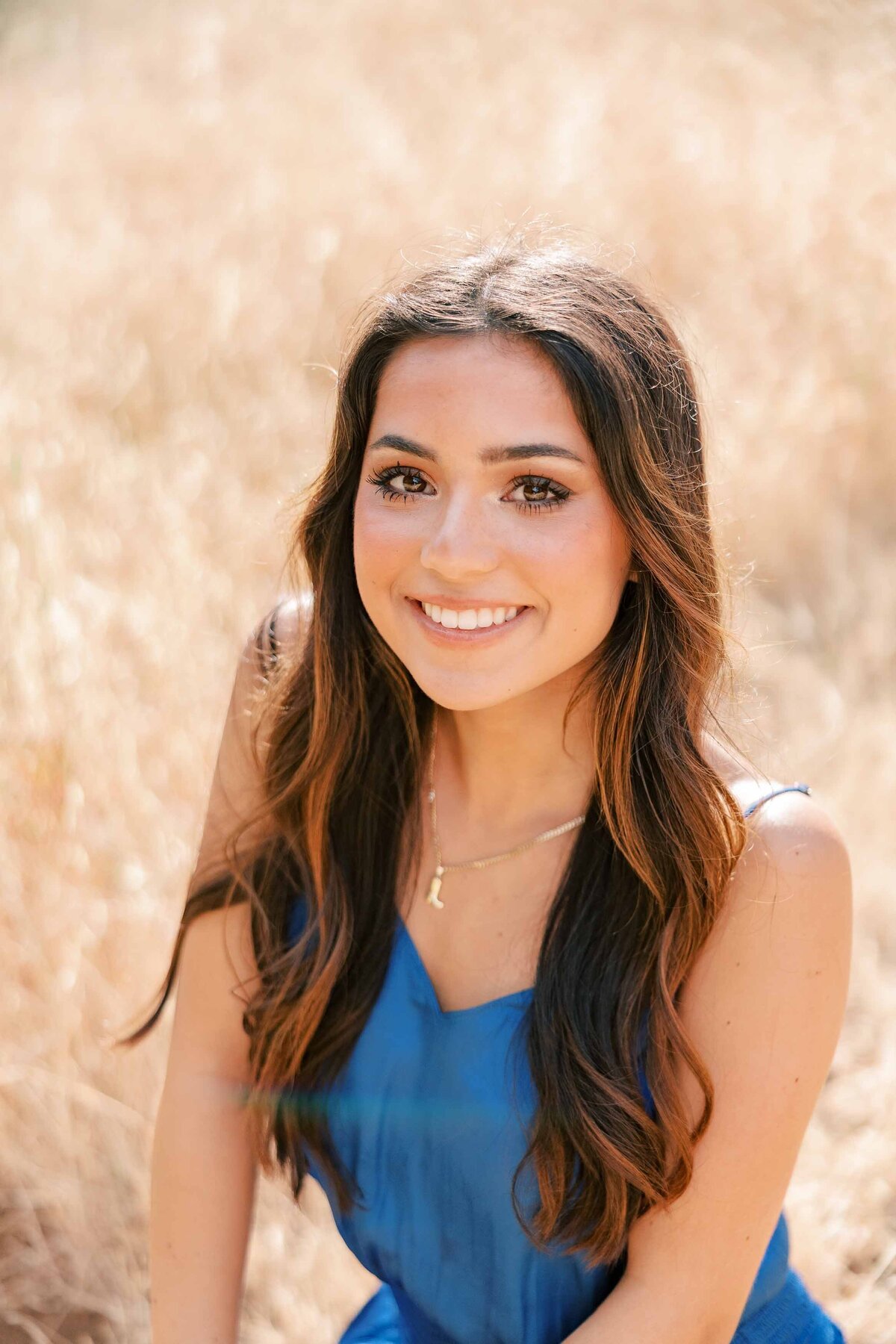 Brunette girl wearing a royal blue dress and looking up at the camera with a soft smile