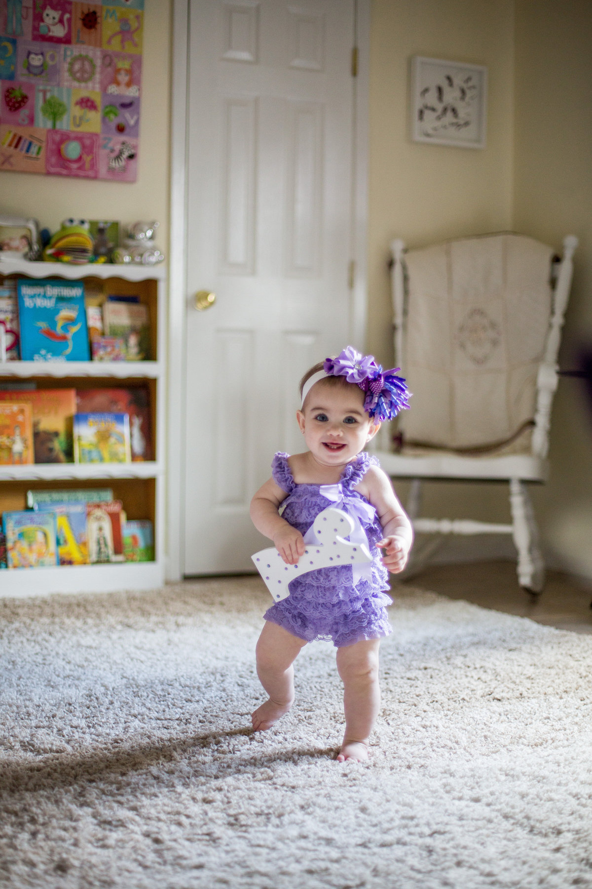 One year old toddler walking in her nursery during an in home photography session in San Antonio.