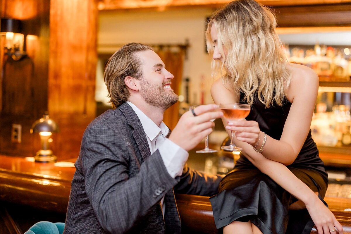City engagement photos celebrate a modern couple's love story on a rainy evening, featuring intimate snuggles and cheers at a Minneapolis club