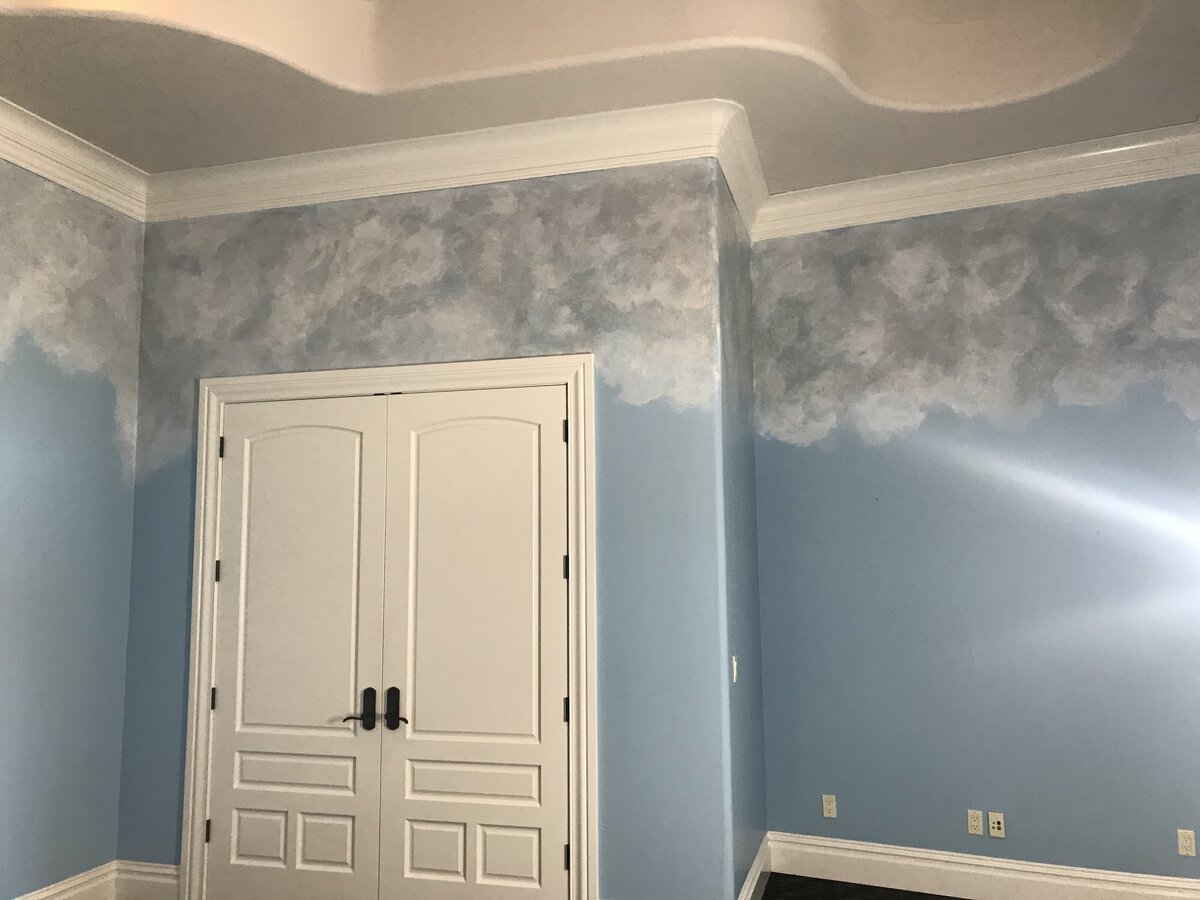 Sky blue bedroom with clouds painted near the ceiling.