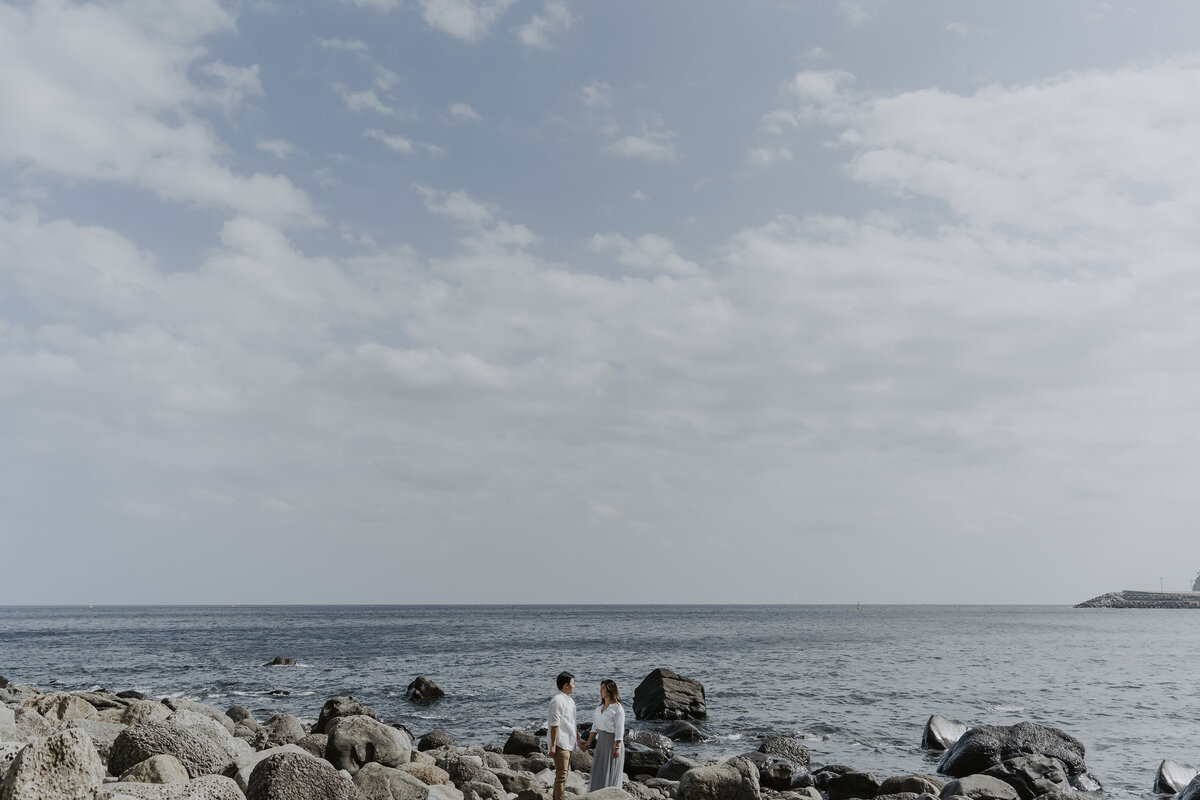 the couple standing on rocks in Gwangchigi Beach while facing each other