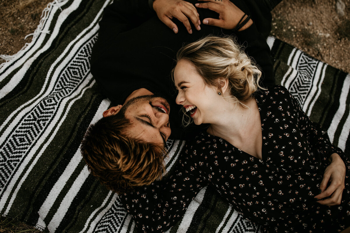 couple laying on a blanket laughing outdoors