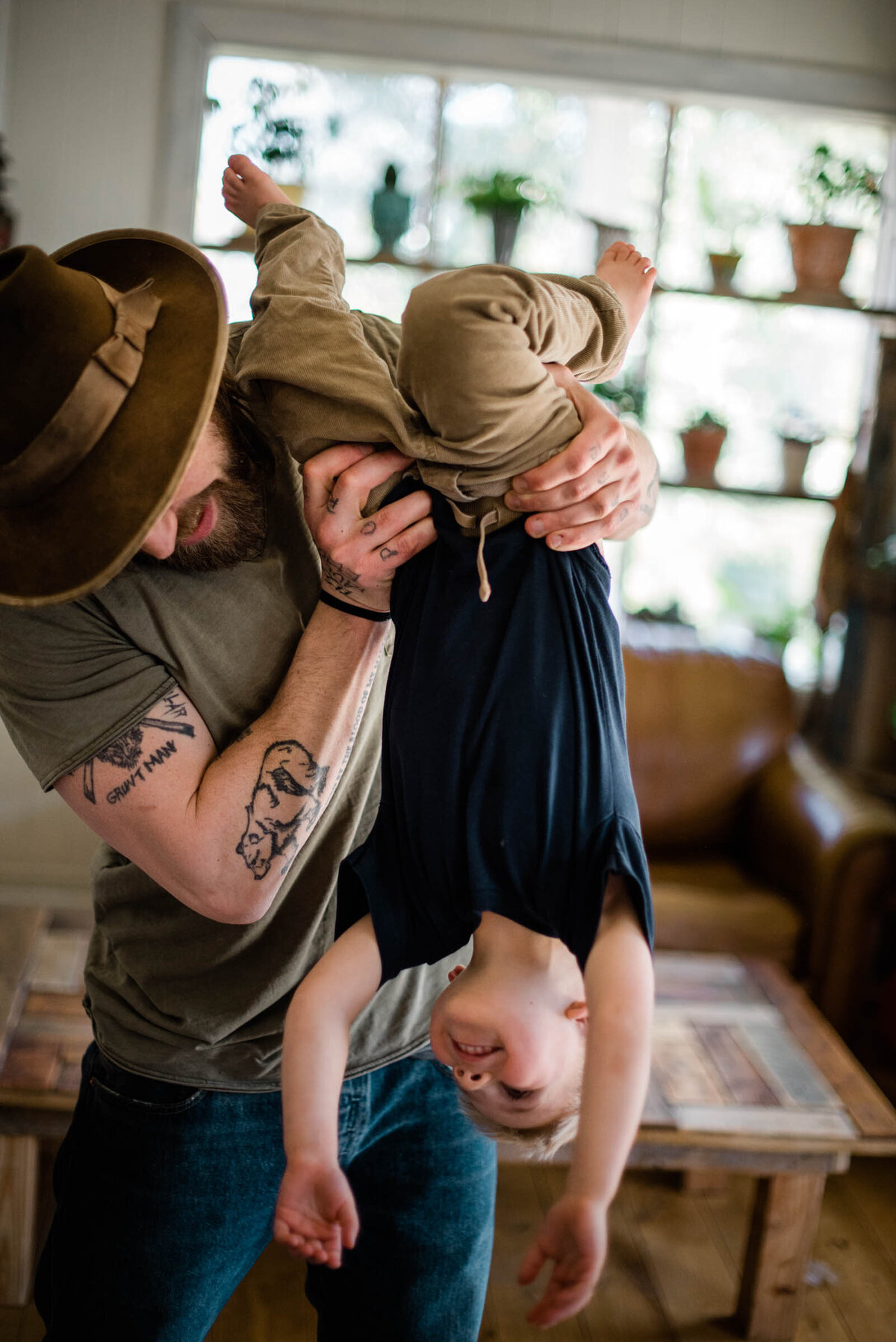 Father holds son upside down in their living room