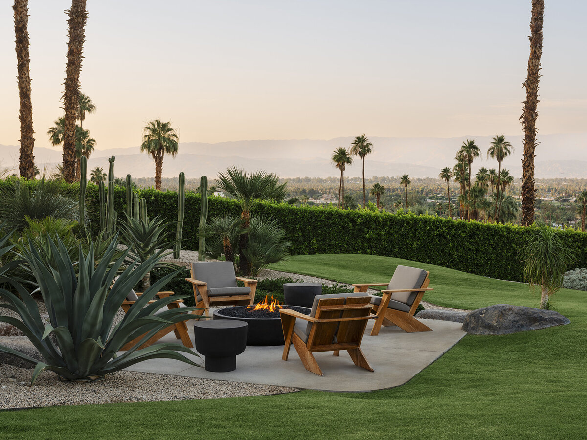 Infinity pool with boulders in landscape and mountain and palm tree views in Palm Springs