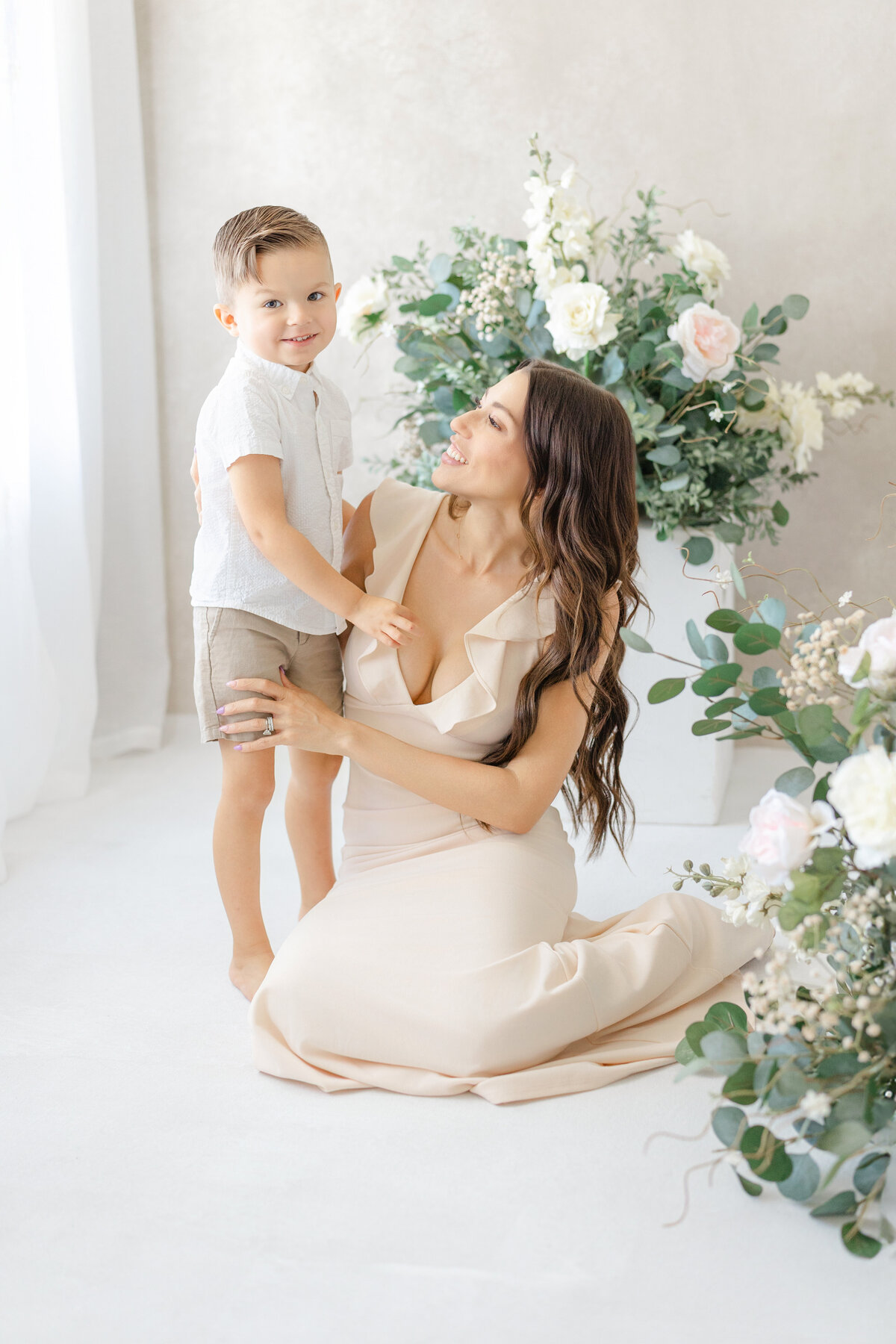 Joyful Tampa motherhood portrait of mom and son laughing together in soft natural light studio