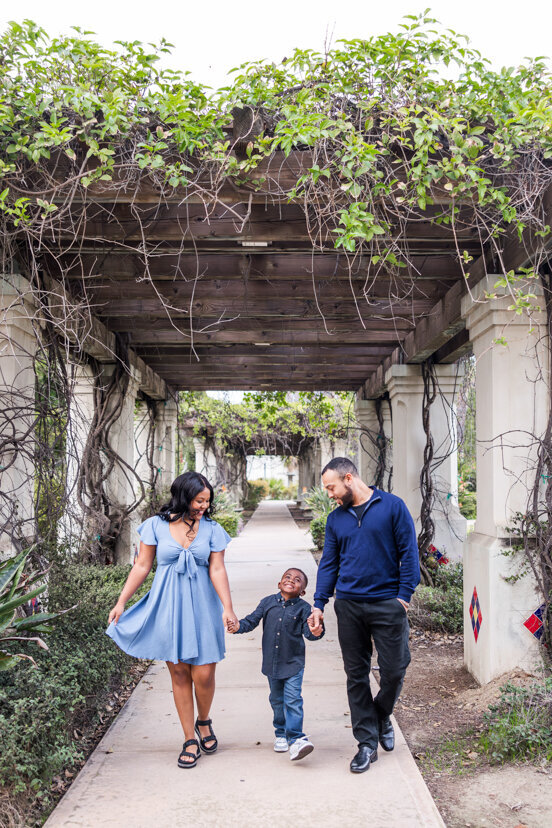couple holding hands and walking with young son balboa park san diego