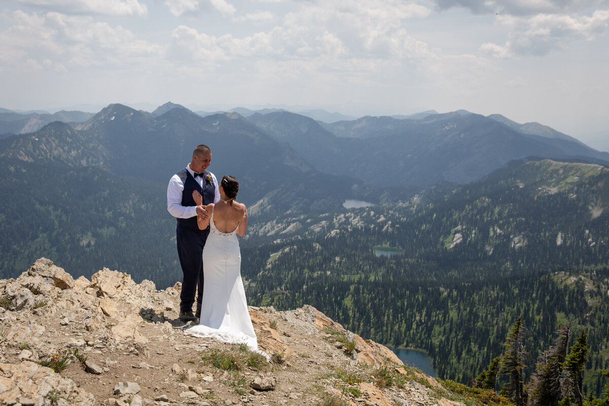 A bride and groom stand facing each other while their Montana elopement photographers take their pictures.