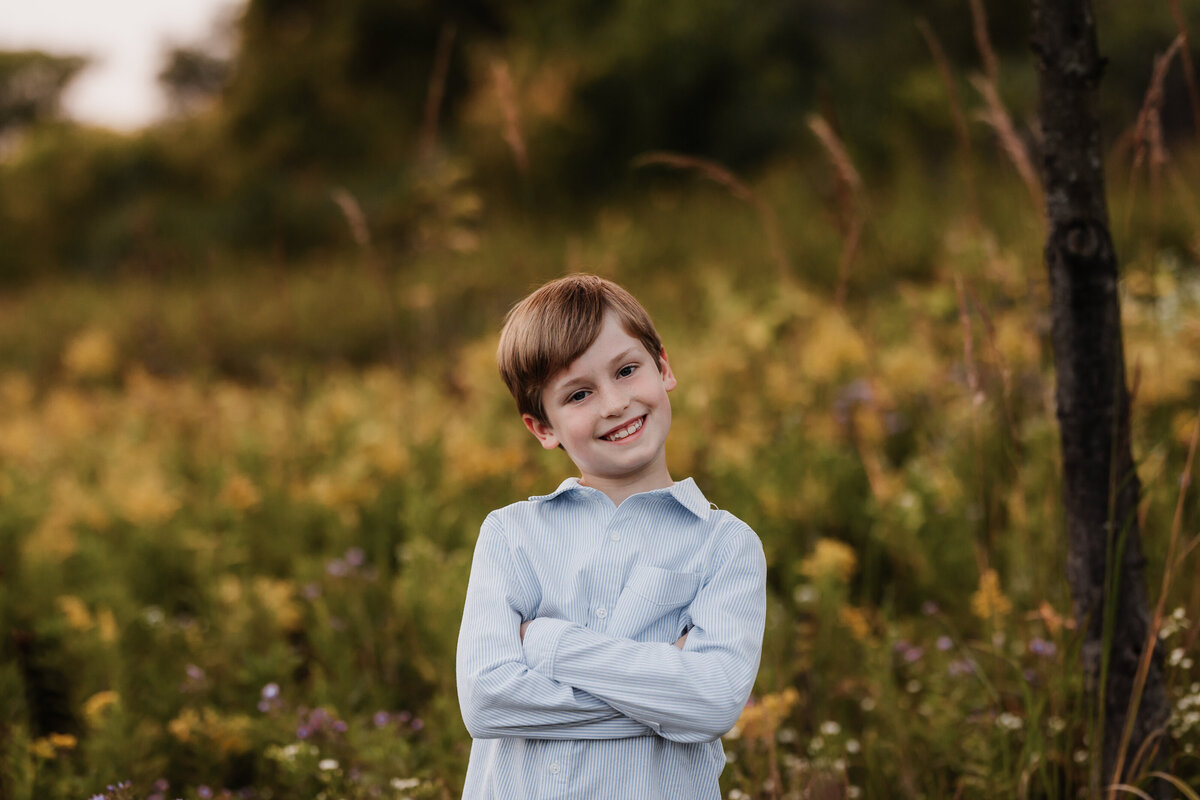 A young boy poses for a portrait in yellow flowers.