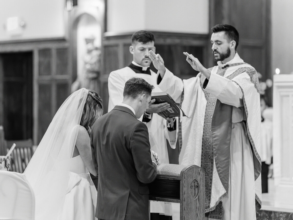 Priest praying over bride and groom during St James Catholic Church wedding in Falls Church, Virginia
