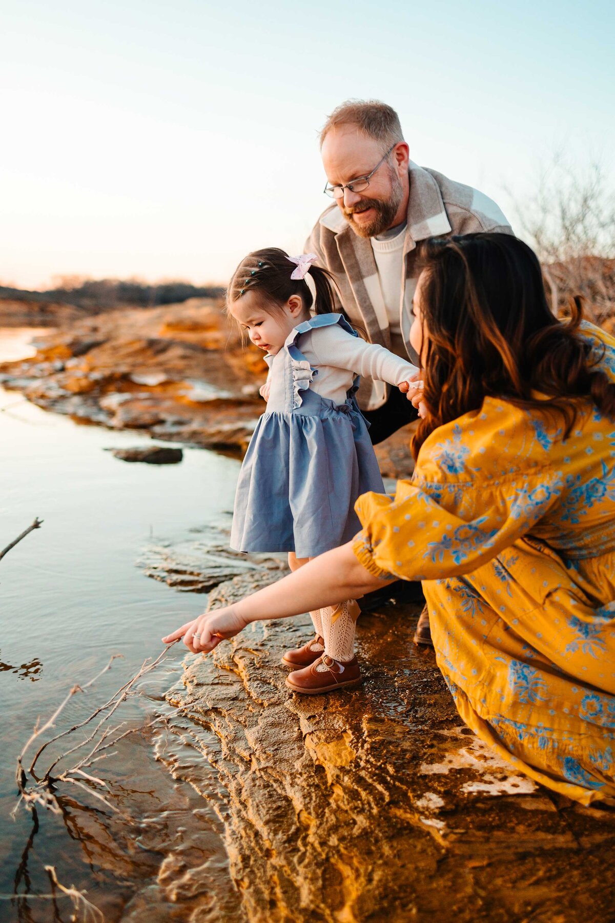 Captured by a professional photographer in Albuquerque, this beautiful family moment shows parents playfully interacting with their little daughter in the water.