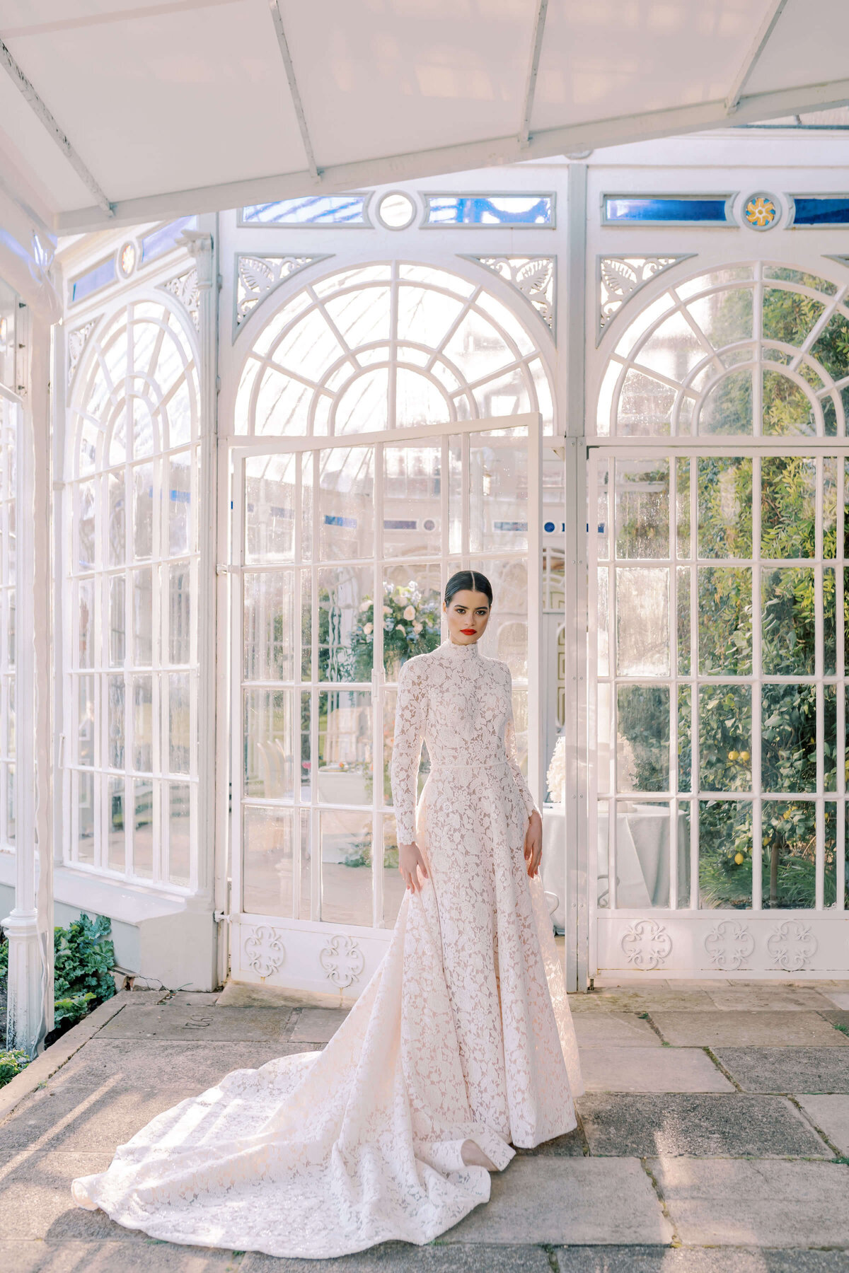 orangery glasshouse at luxury wedding venue avington park with a bride in a lace white dress standing in front of it to pose during golden hour