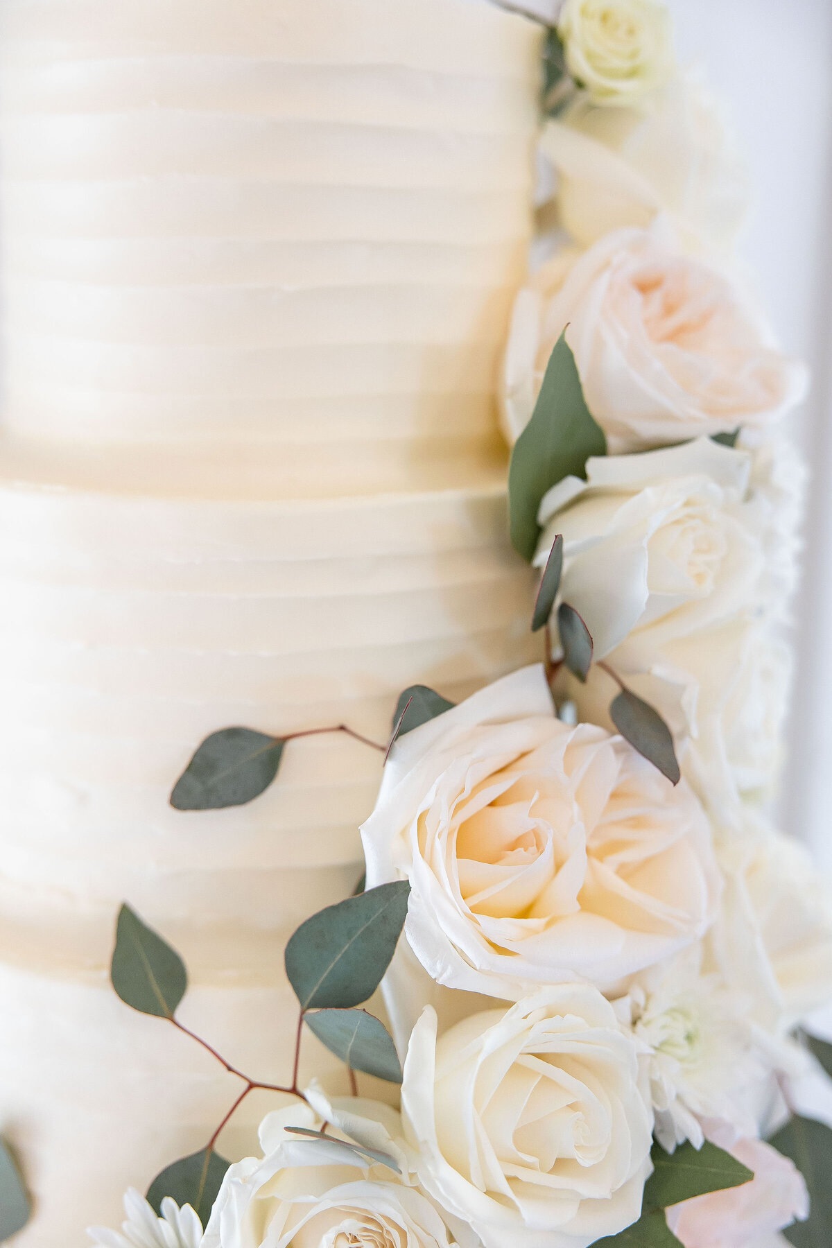 wedding photographer in Texas captures white roses spilling along the side of a white 3 tier cake