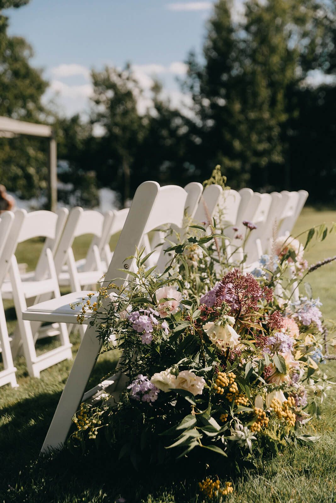 24.ceremony-floral-arrangement-white-chairs-colorful-wedding-flowers