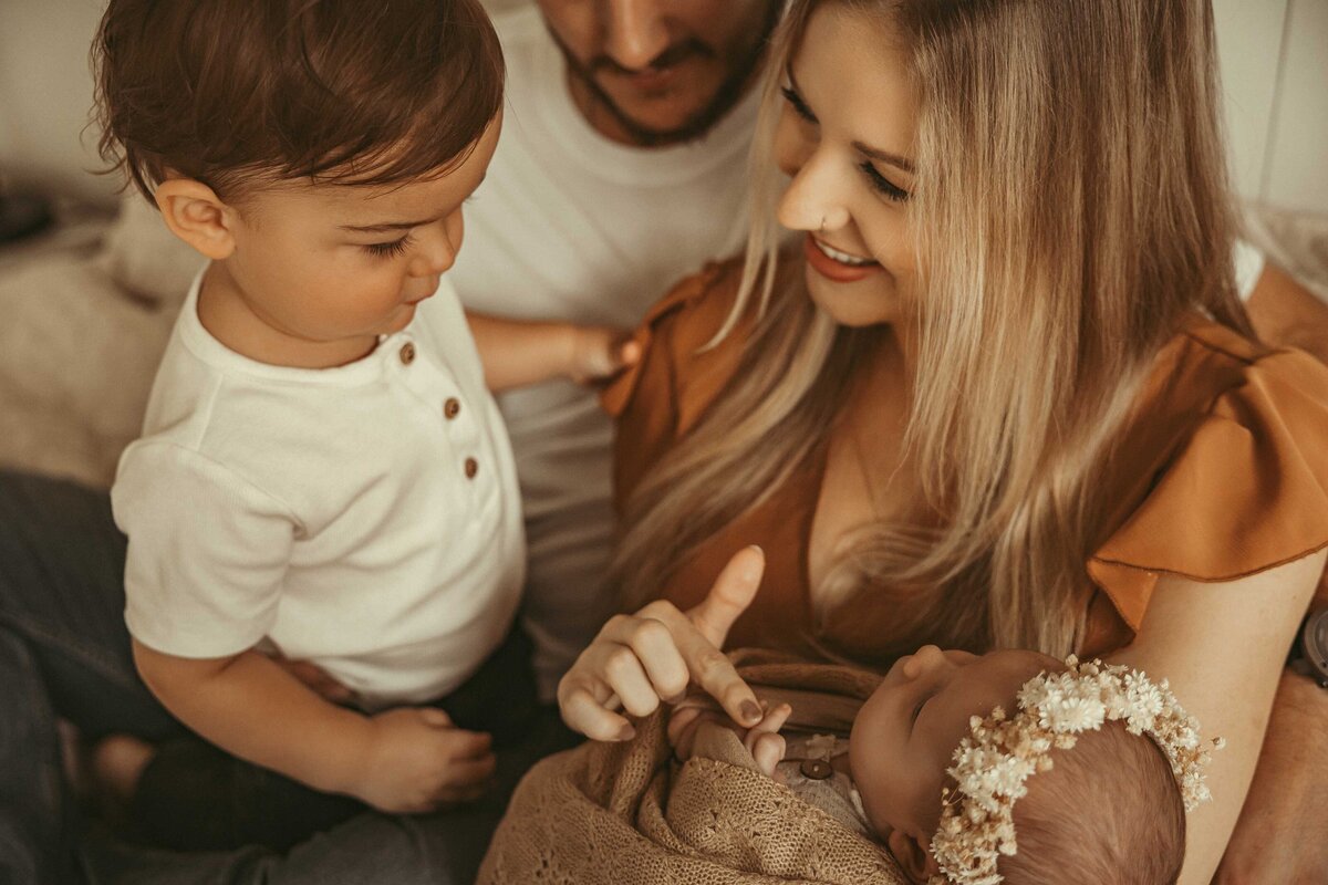 family looking at their new baby girl whil sitting on the floor