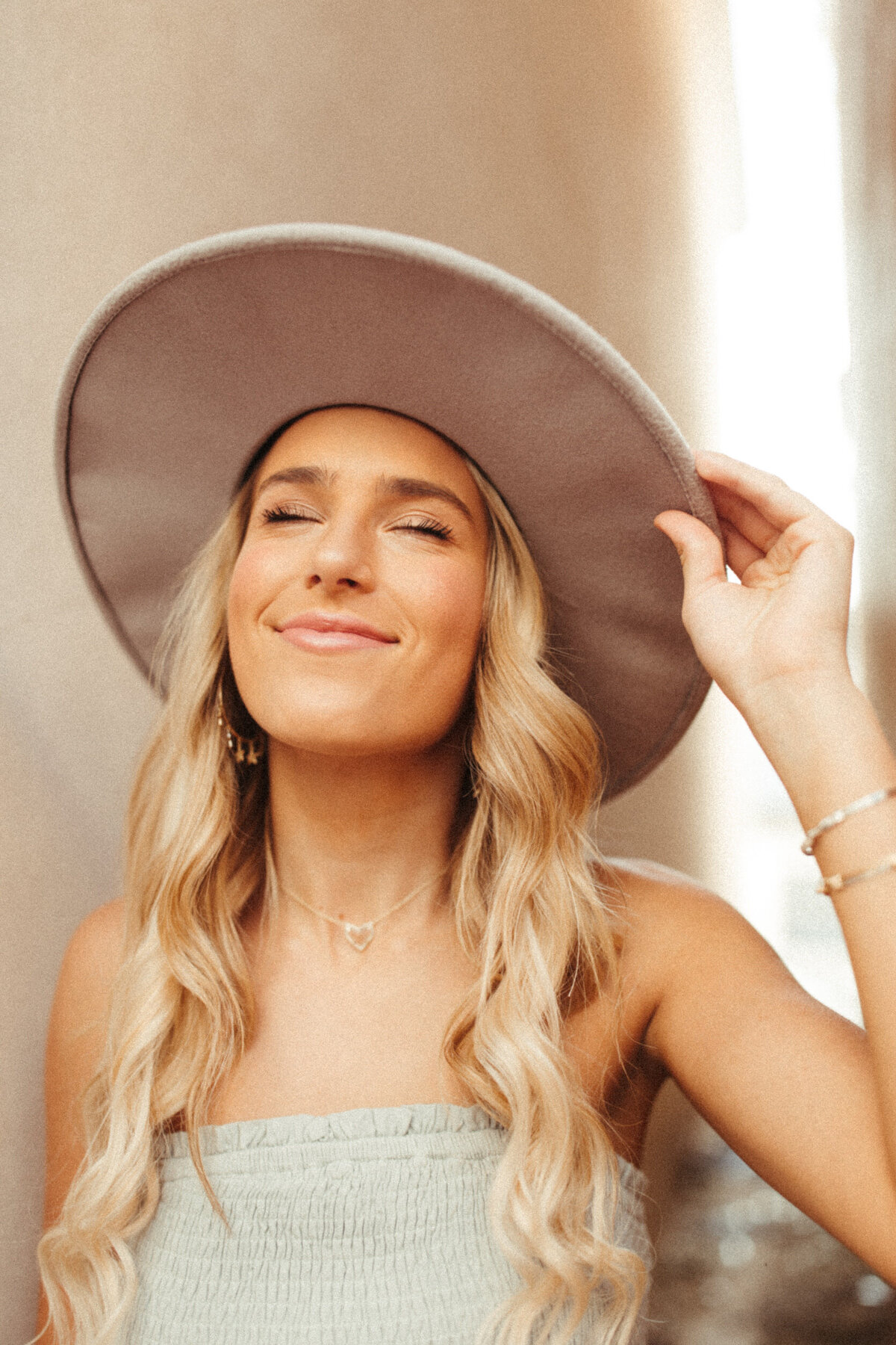 Girl senior in wide brimmed hat soft smiling with her eyes closed