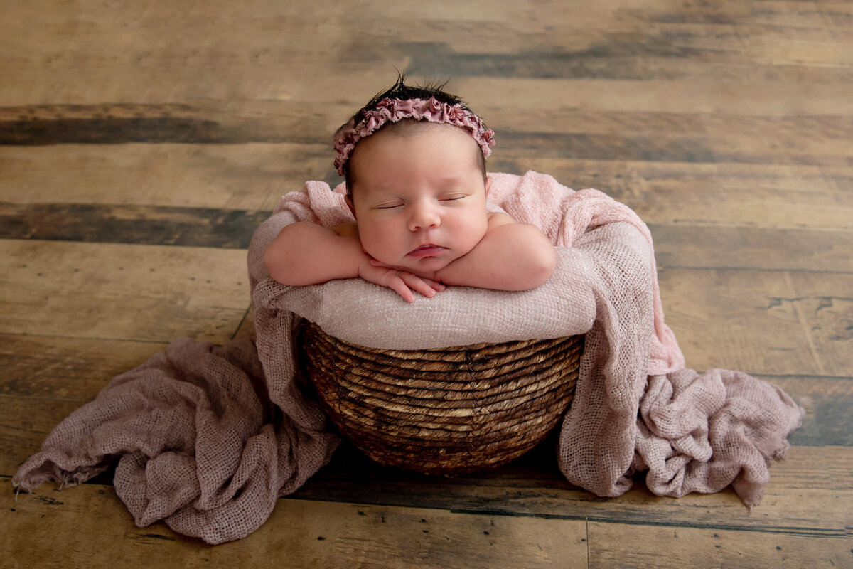 newborn baby girl in a basket with a pink blanket over her for her Burlington Newborn Photos
