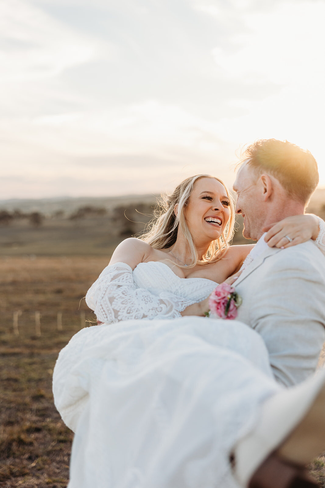Bride smiling in the arms of her groom during sunset wedding portraits at Petrichor Farm