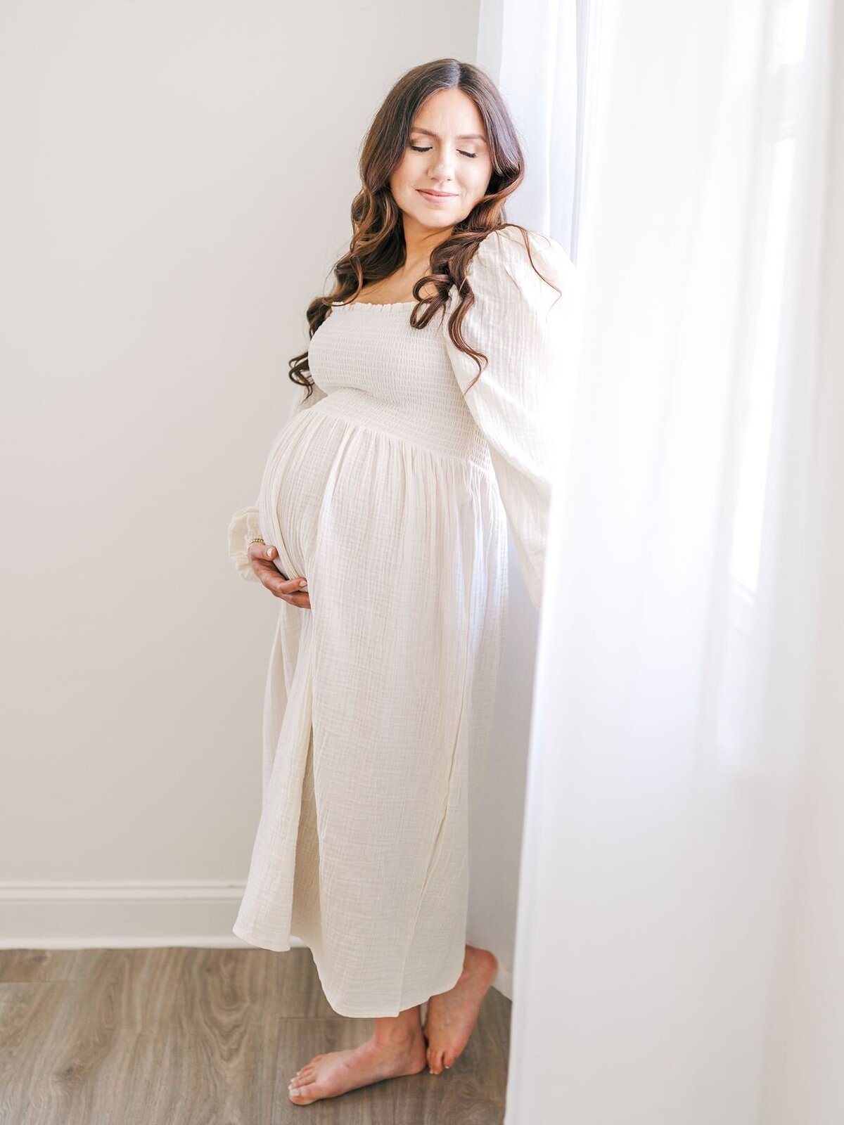 Mom-to-be standing in studio holding baby belly.