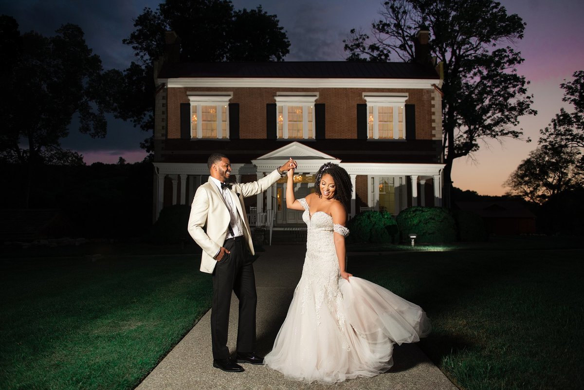 Bride and Groom dancing in front of Ravenswood Mansion during sunset, groom is wearing a white dinner jacket