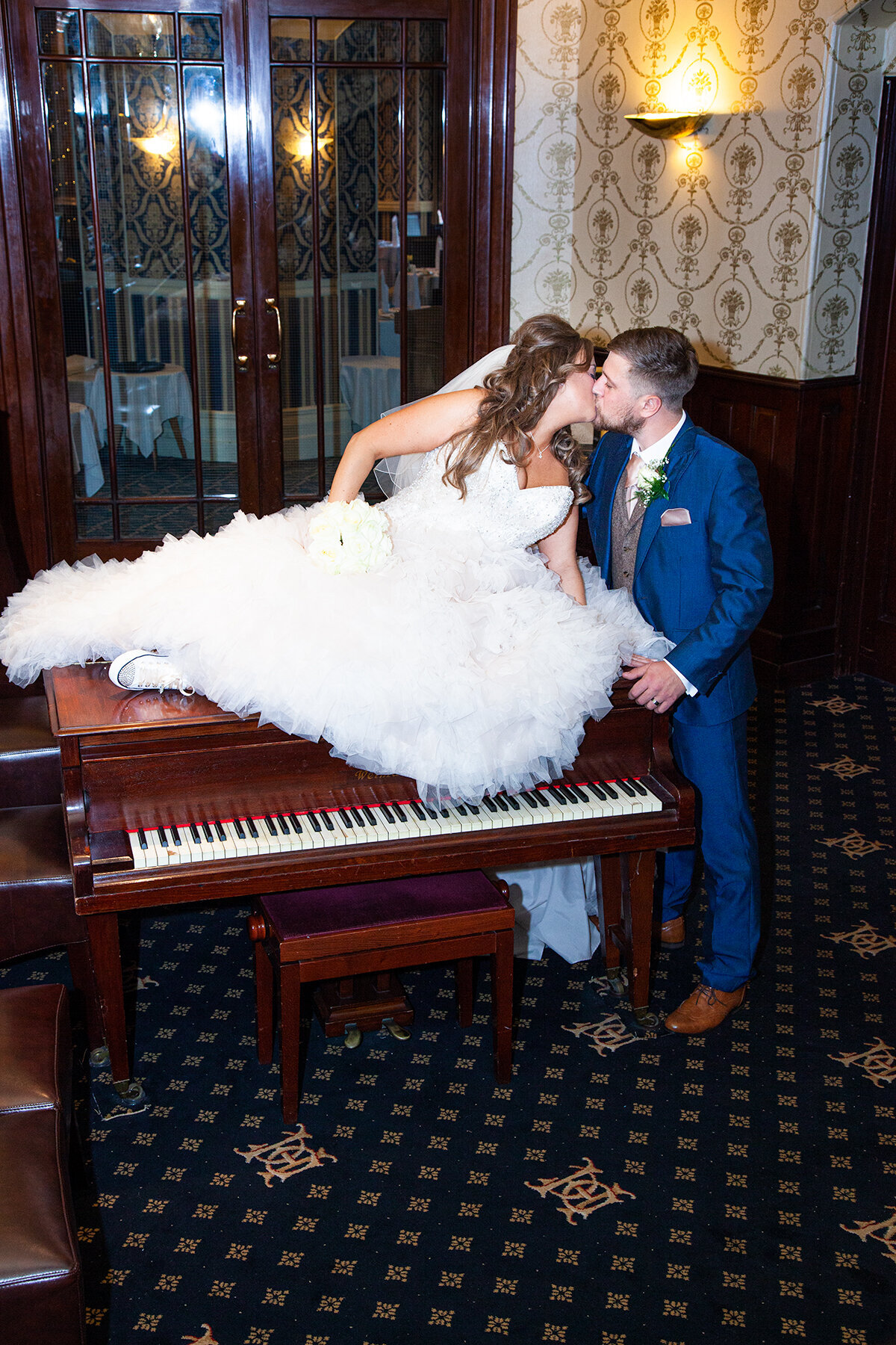 pro-story-photography_bride-sat-on-piano-kissing-groom_duke-of-cornwall-hotel_plymouth